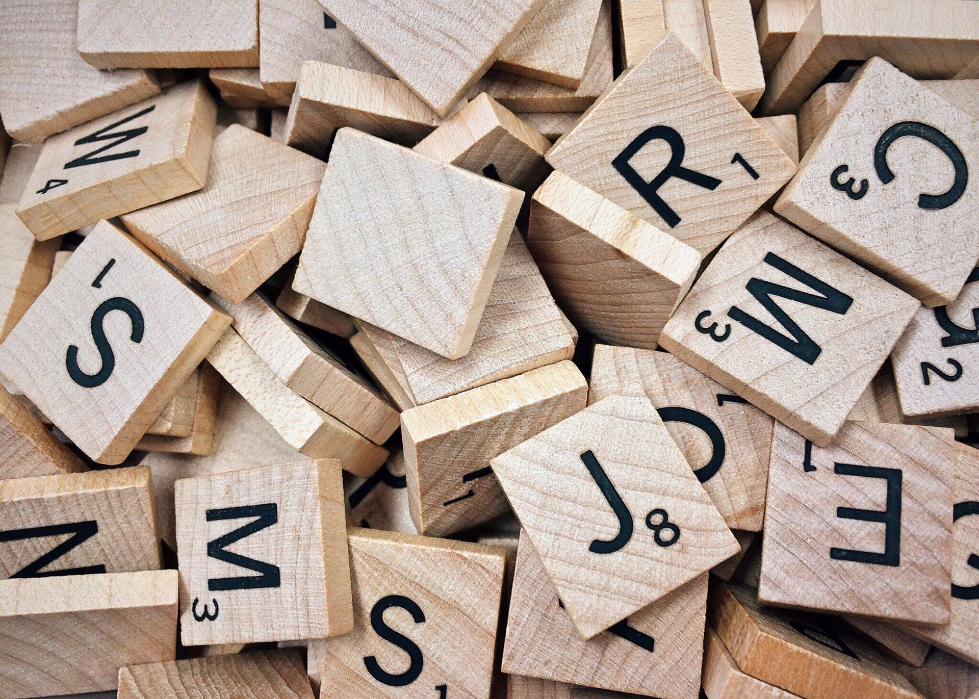 Stacked wooden Scrabble tiles with letters and point values