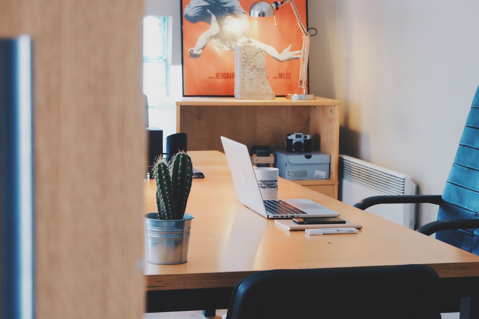 Modern desk setup with a laptop, cactus plant and stylish decor