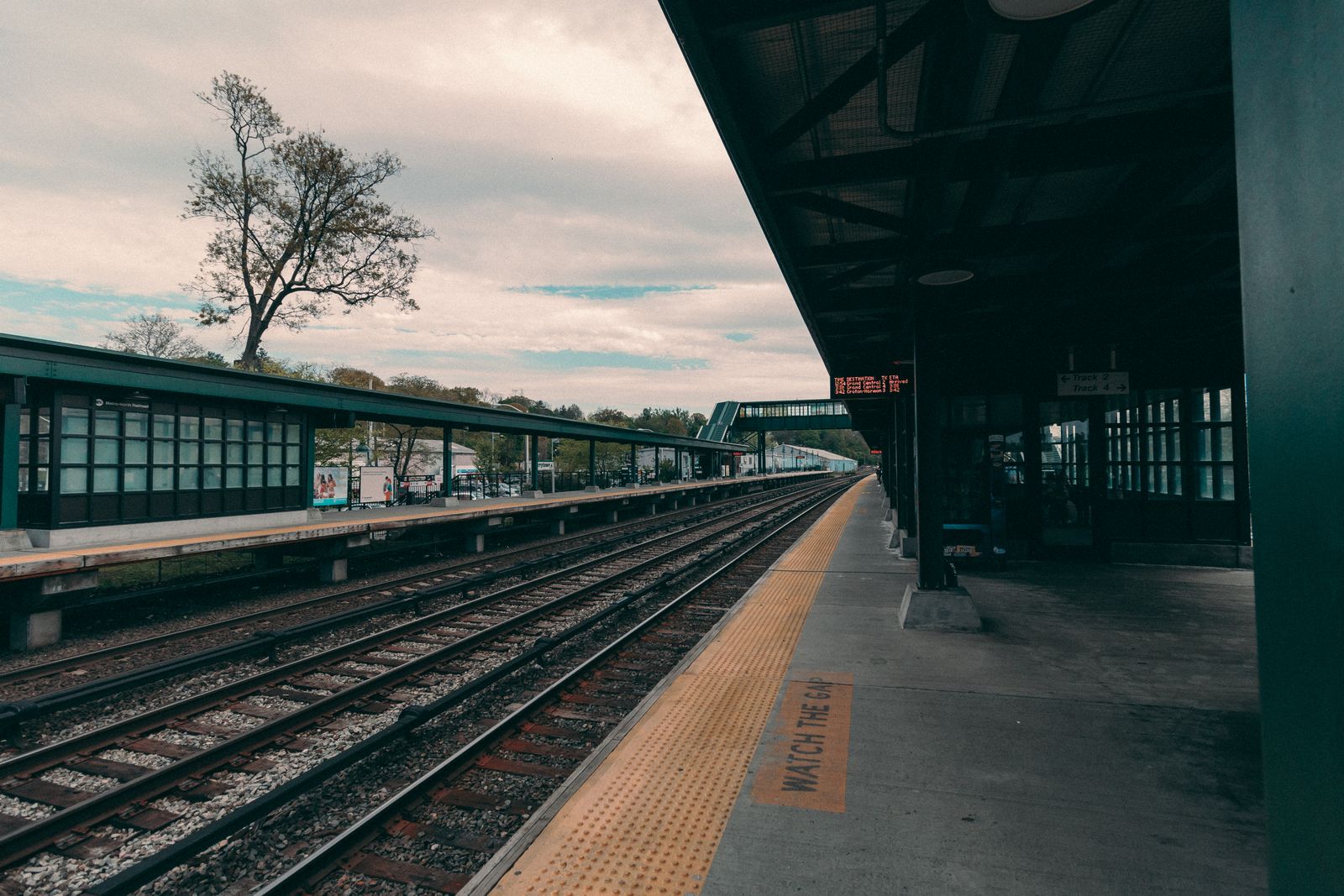 A serene view of an empty train station platform under a cloudy sky