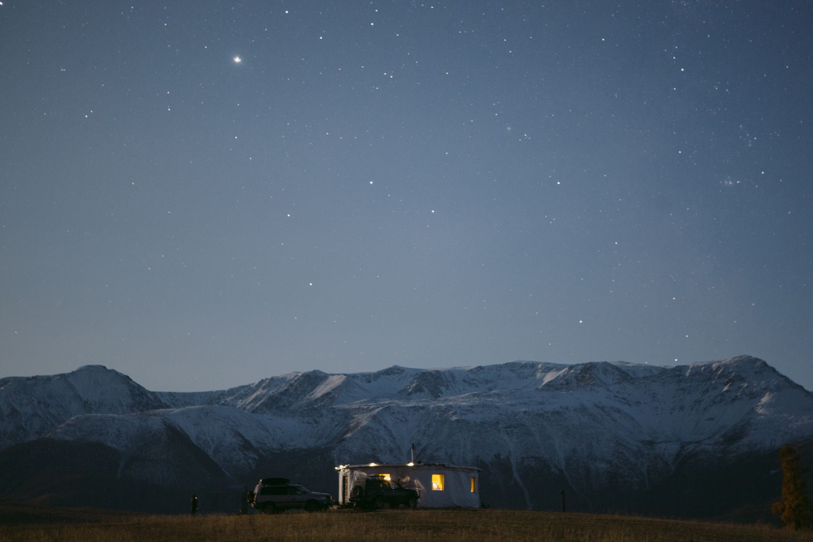Serene camping scene under a starry sky with snowy mountains