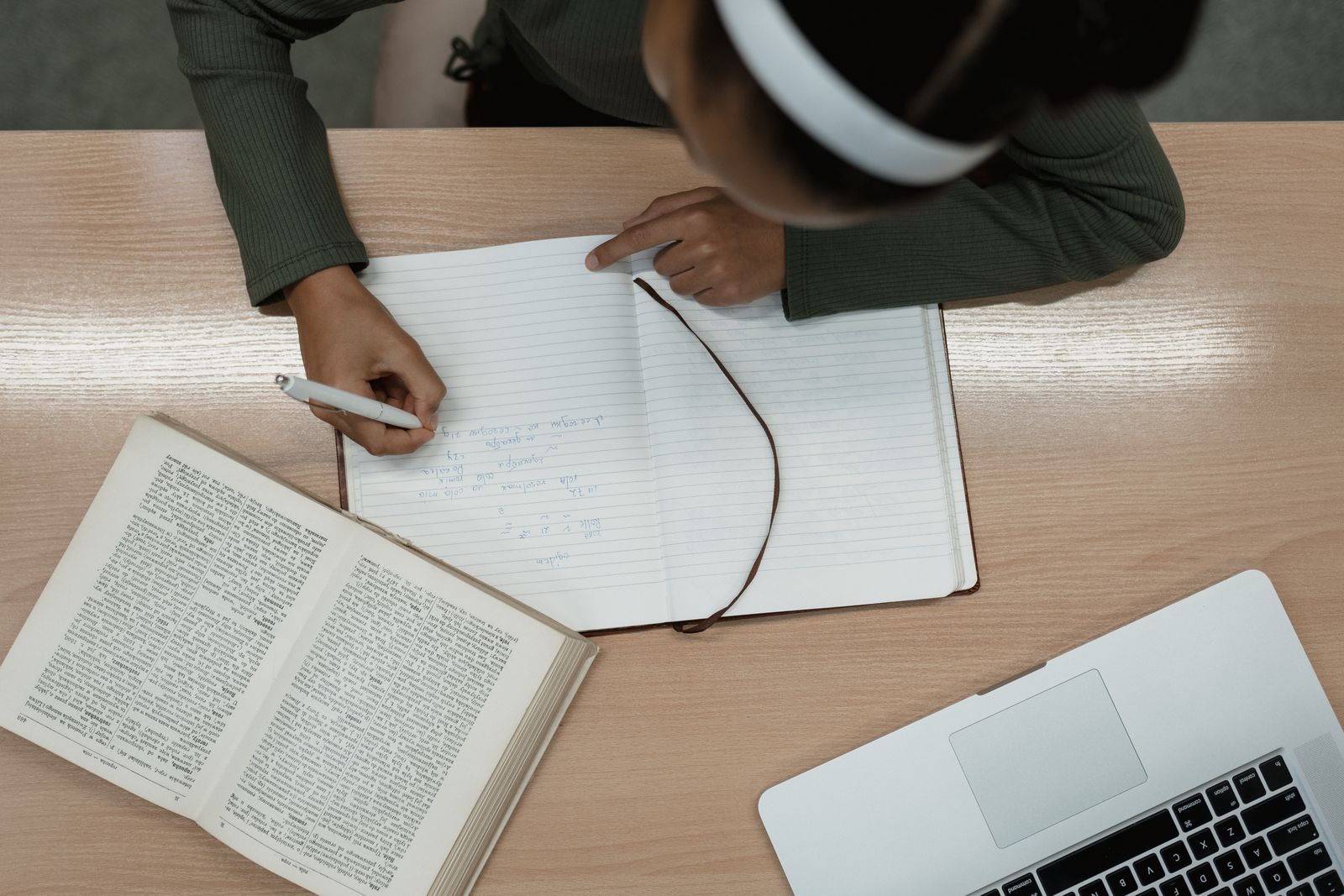 Person studying grammar with pen and notebook on desk
