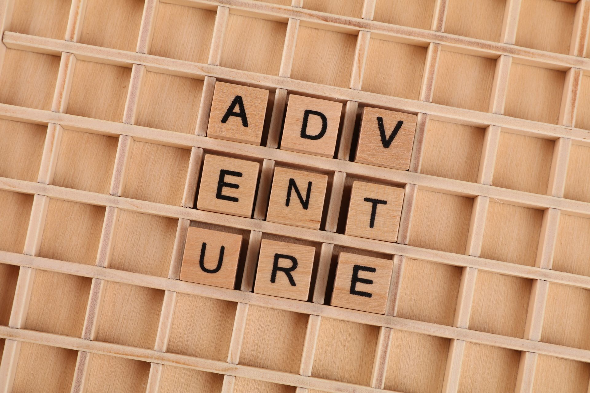 Wooden blocks spelling the German word Abenteuer on a grid