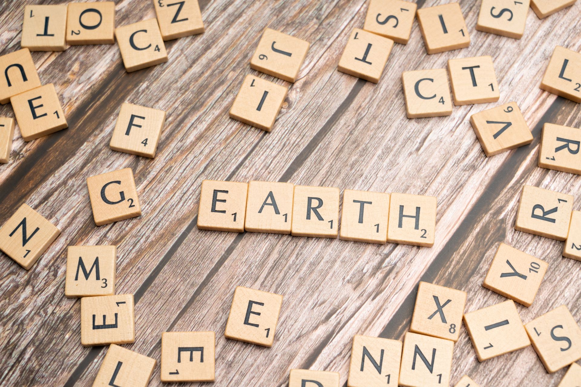 Scrabble tiles spelling Earth surrounded by random letters