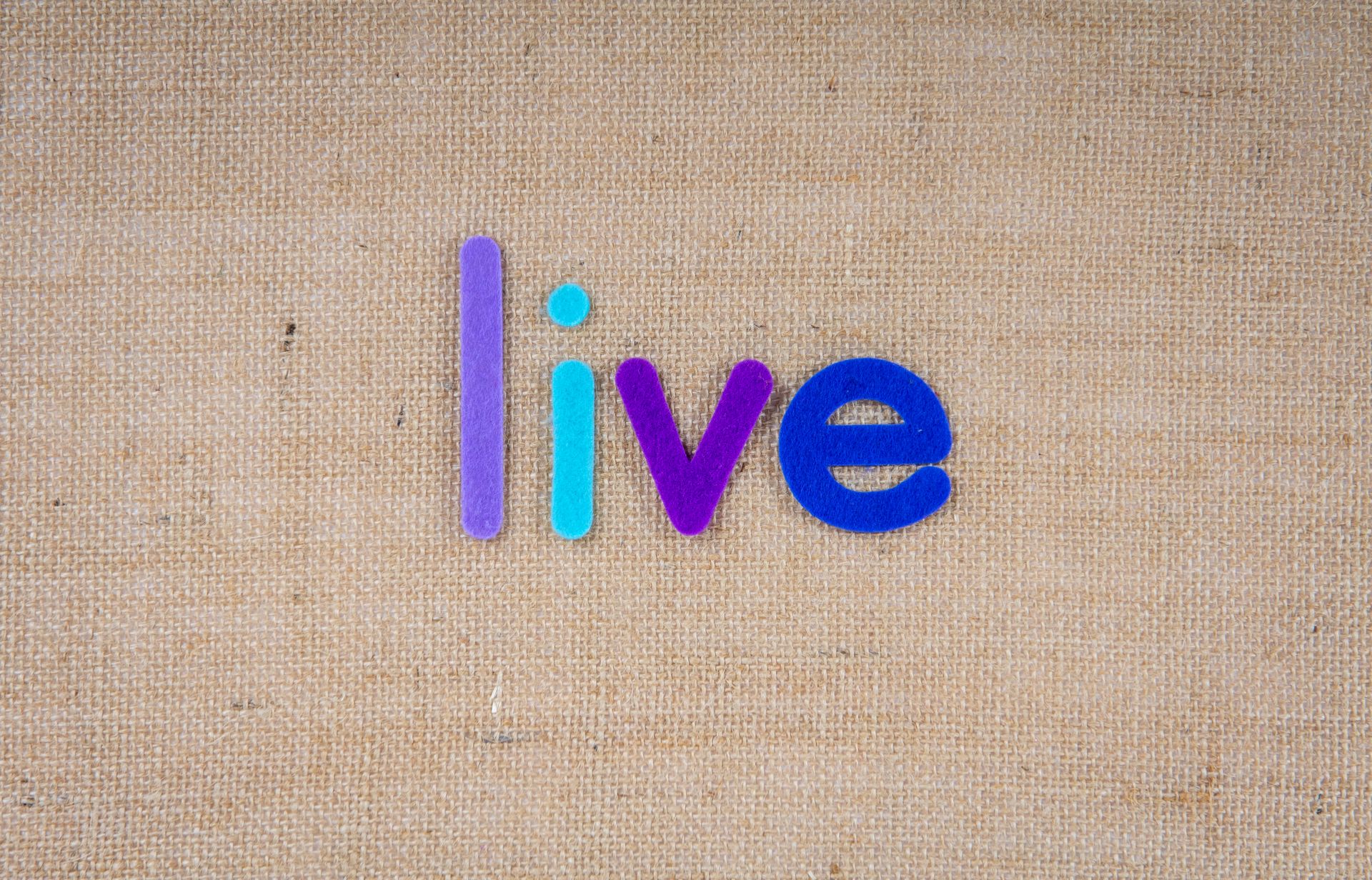 Colorful wooden letters spelling live on burlap
