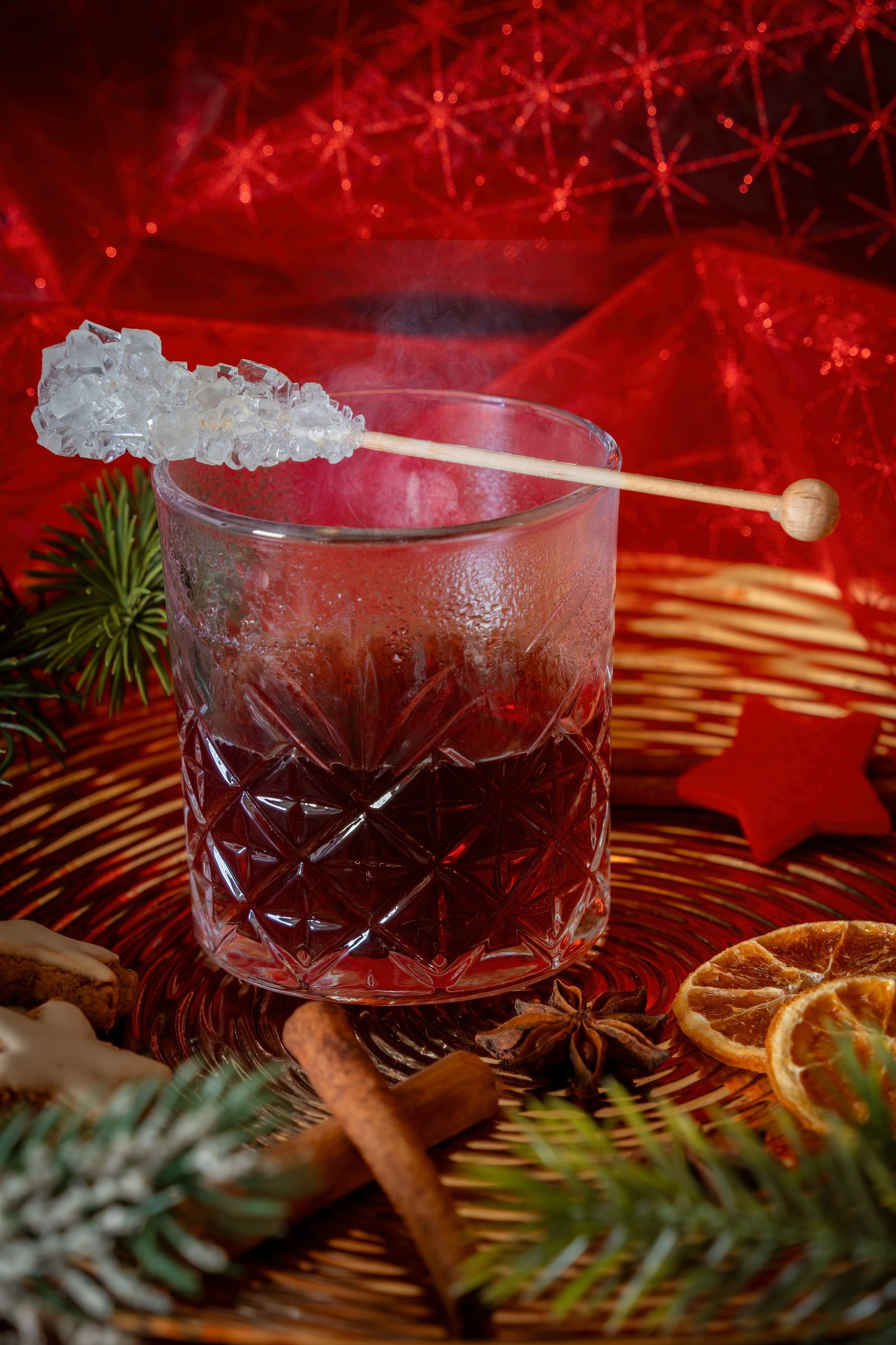 Glass of warm Gluhwein surrounded by holiday spices and decorations
