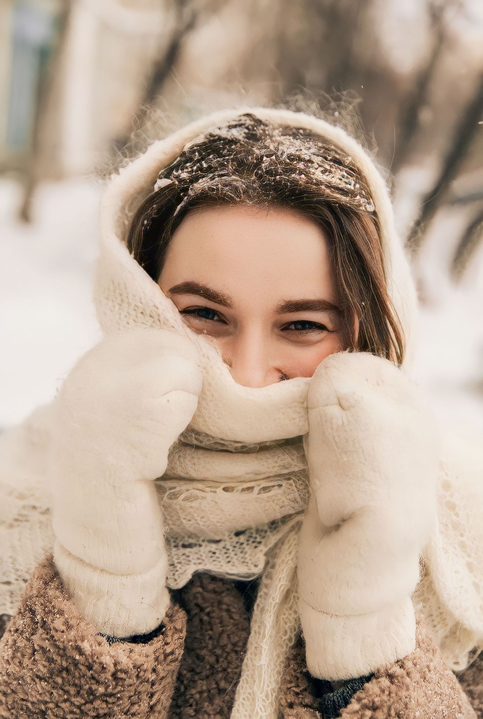 Smiling woman in cozy winter attire in a snowy outdoor setting