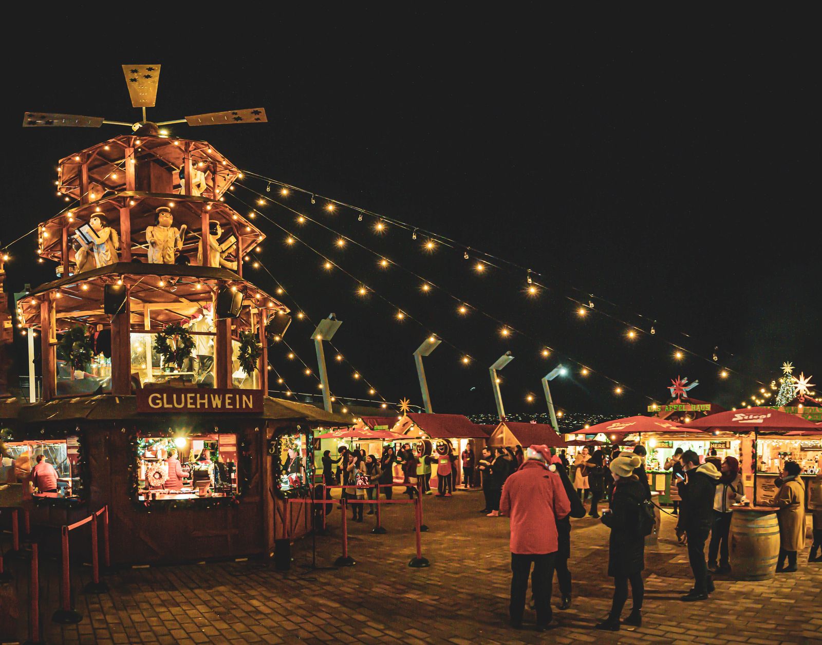 Night scene at a Christmas market with lights and a Gluhwein stall