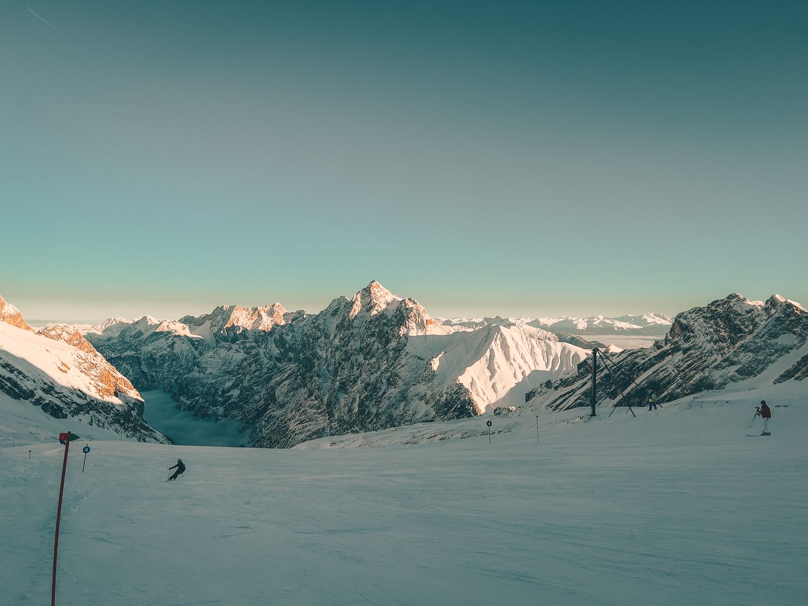 Skiers on snow-covered mountains under a clear sky