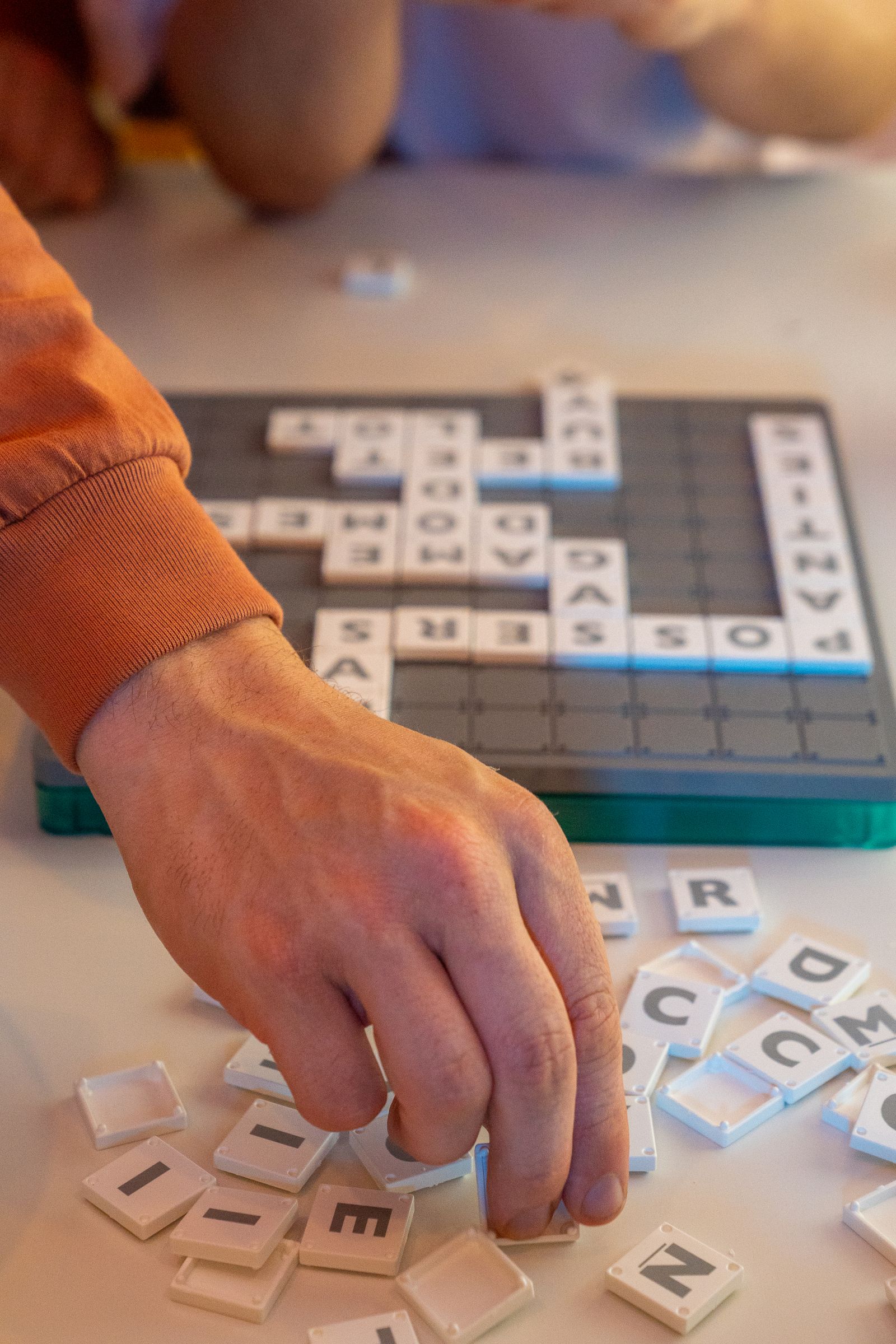 Hand placing Scrabble tiles on a board during a game