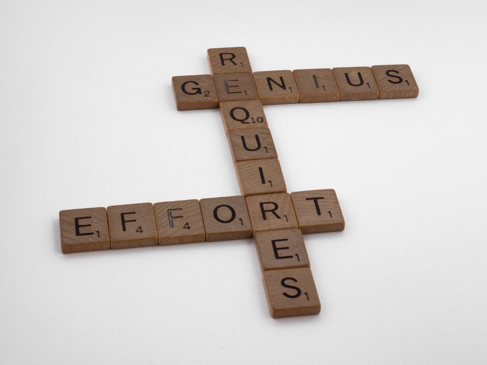 Wooden Scrabble tiles arranged spelling words on a white background