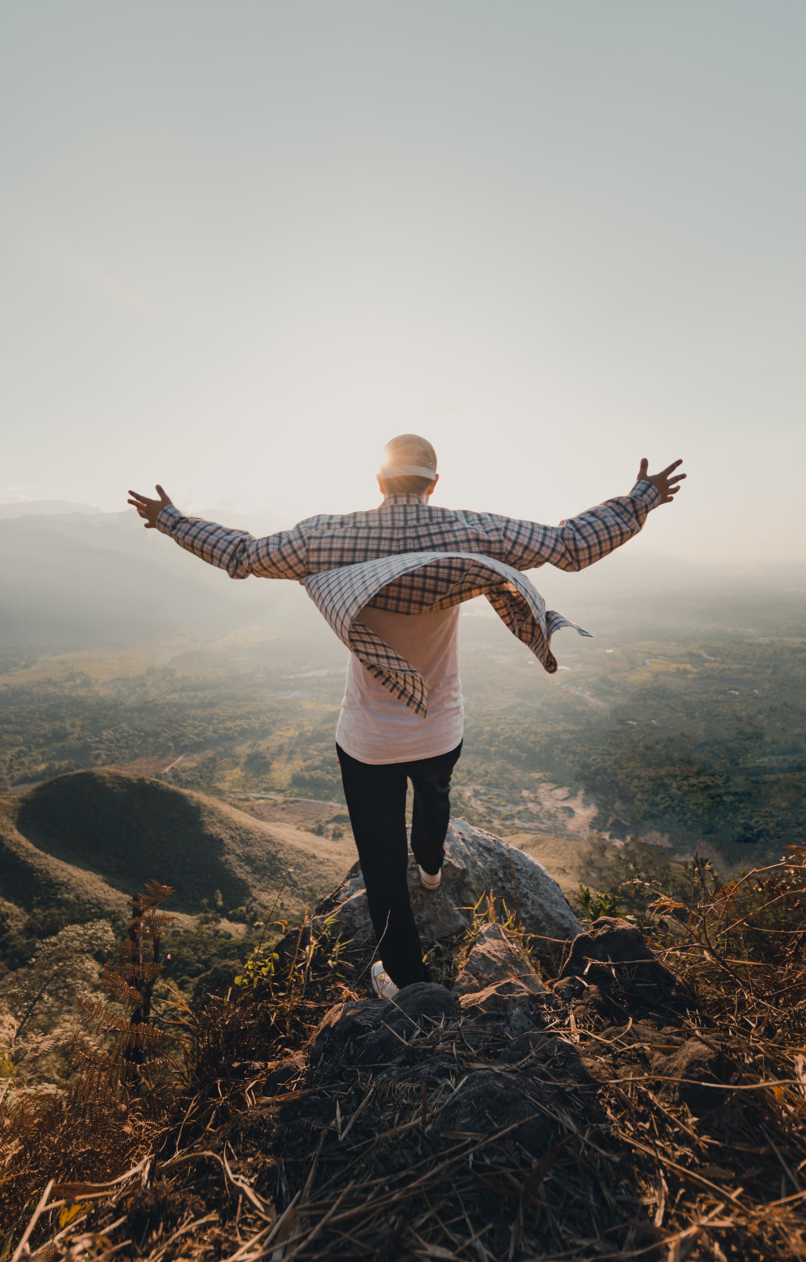 Person with open arms on a mountain top at sunrise