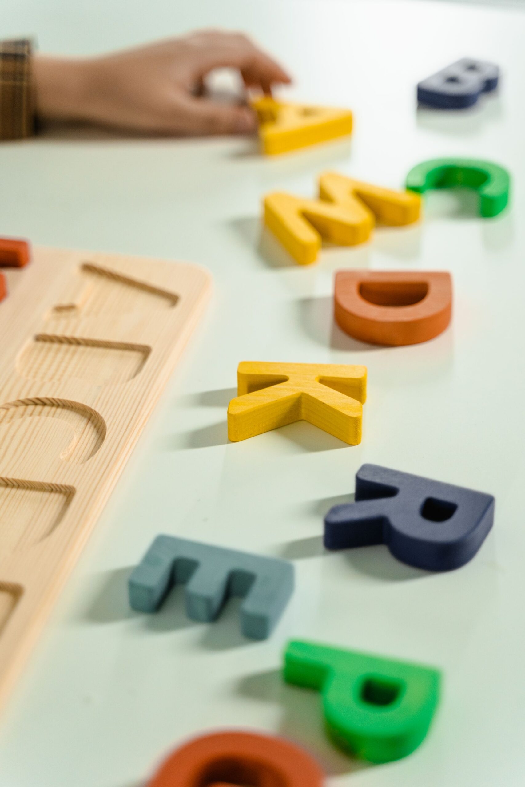 Colorful wooden alphabet letters scattered on a white surface for educational activities.