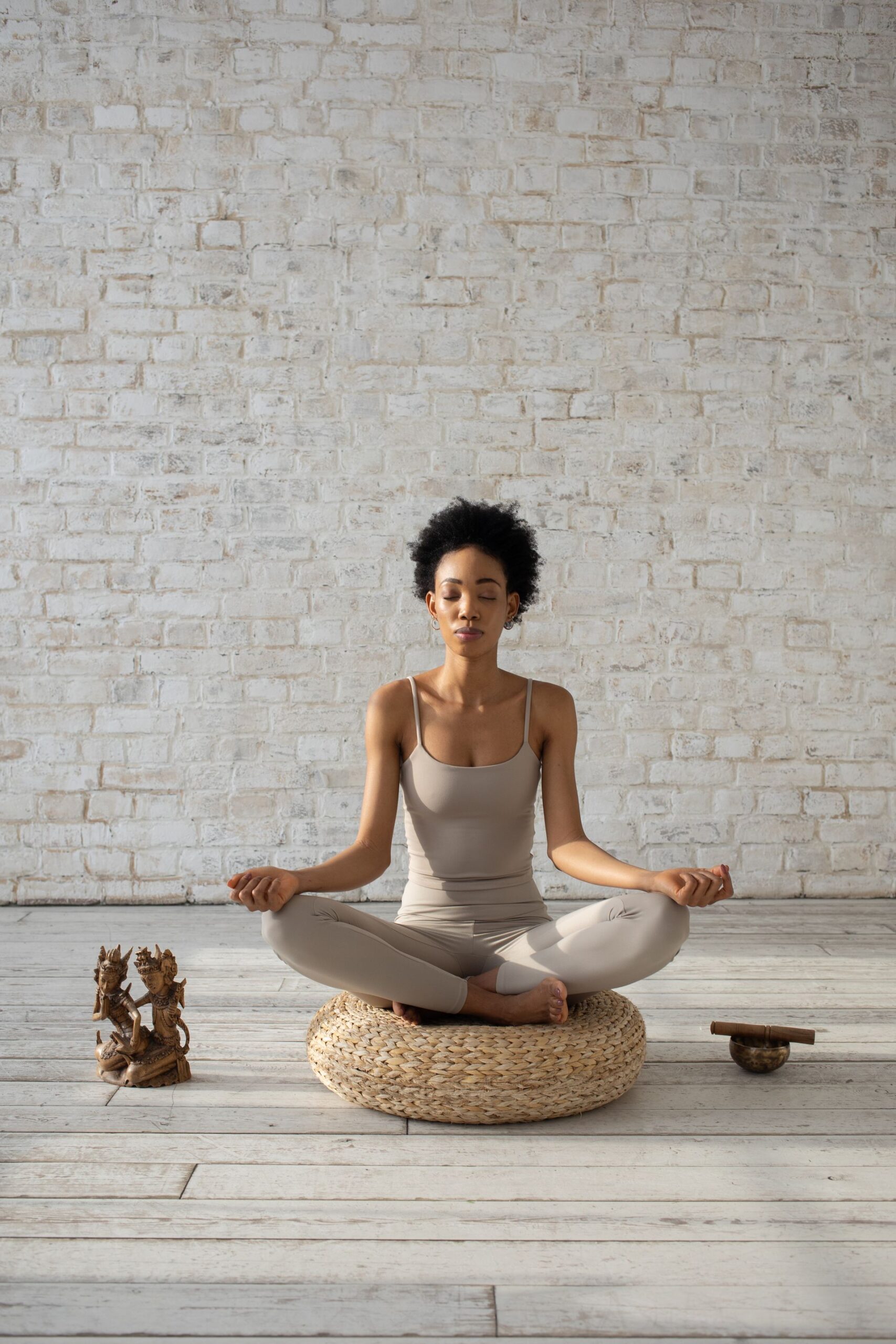Peaceful woman meditating on a cushion in a bright, minimalist room.