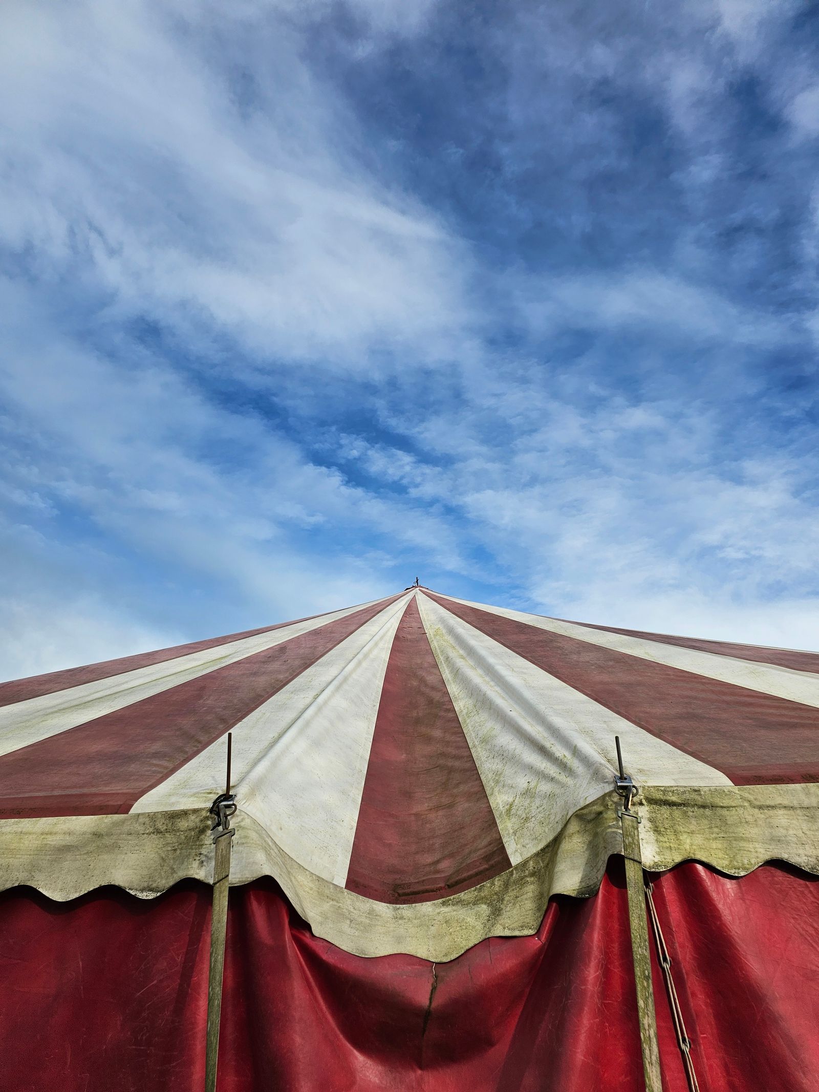 Red and white striped circus tent under a cloudy sky