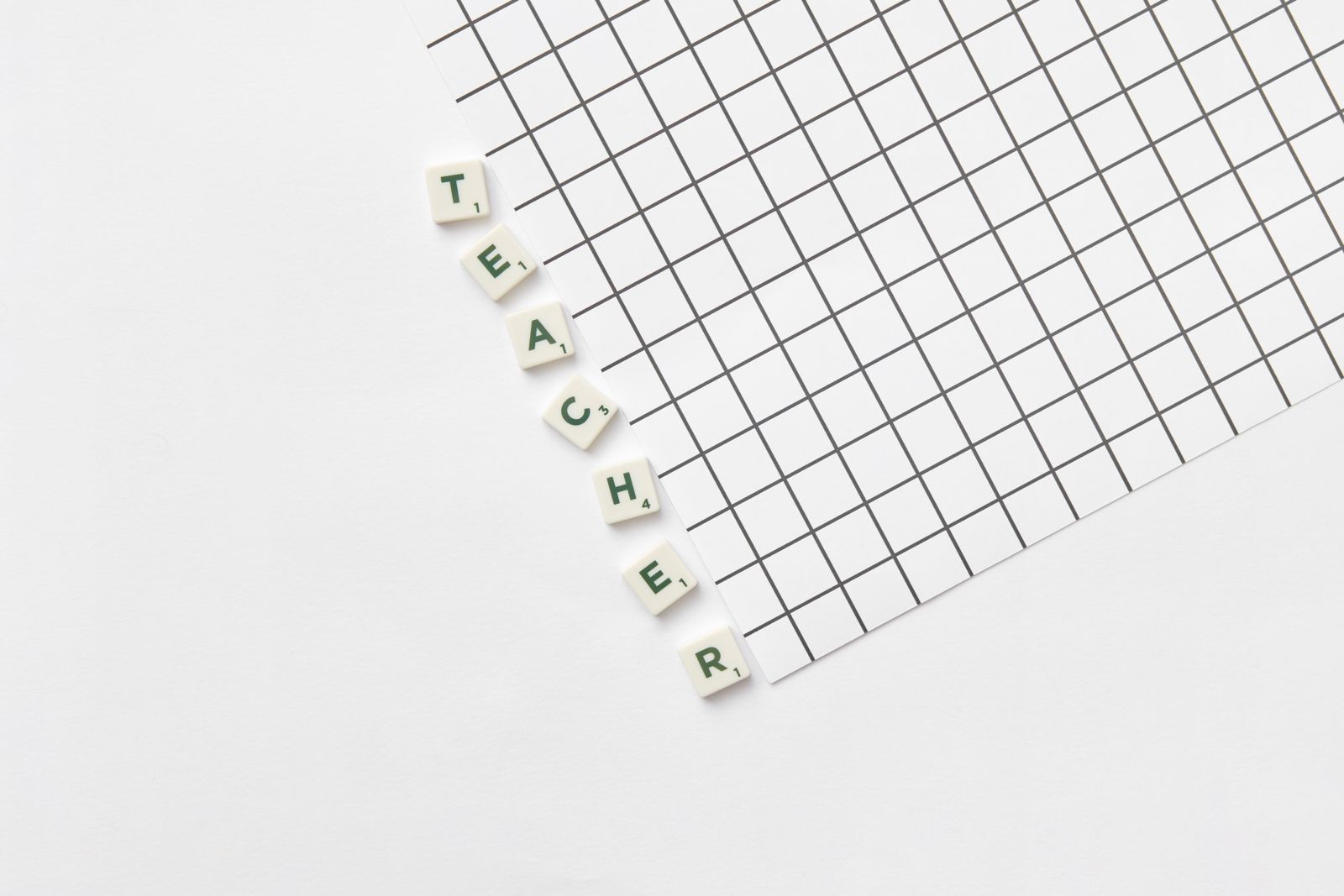 Alphabet letters spelling Teacher on white grid paper
