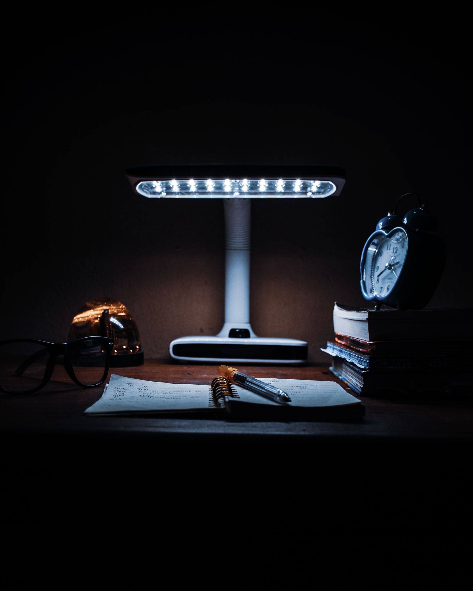Student writing study notes at a desk with lamp