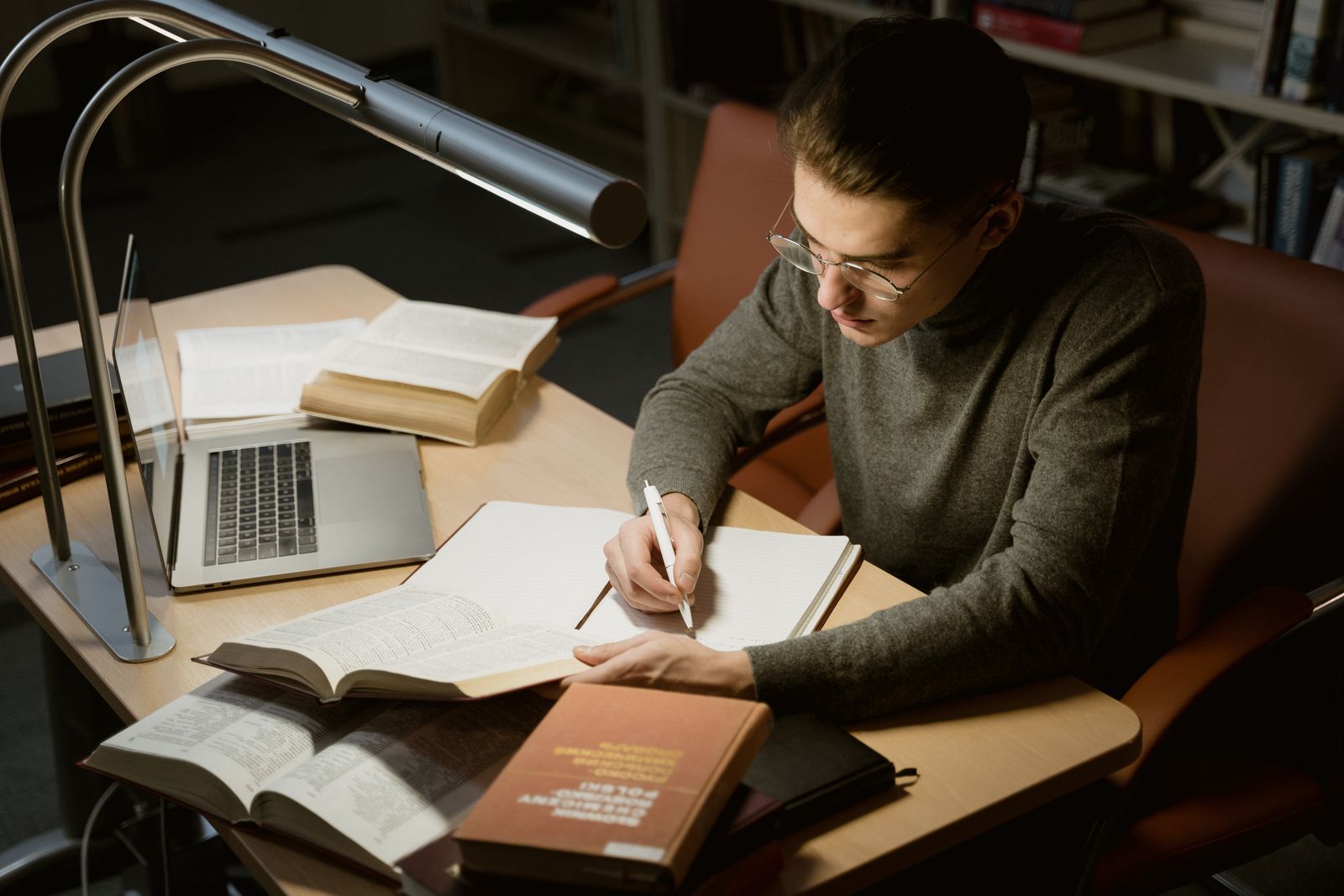 Student writing in notebook during evening study session