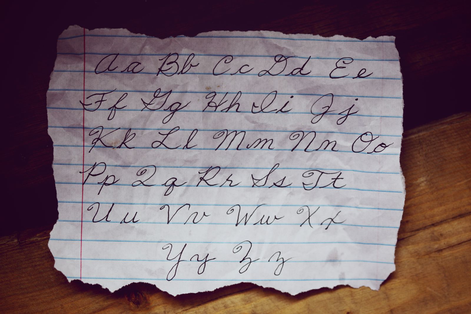 A close-up of cursive alphabet letters beautifully written on lined paper, showcasing elegant handwriting