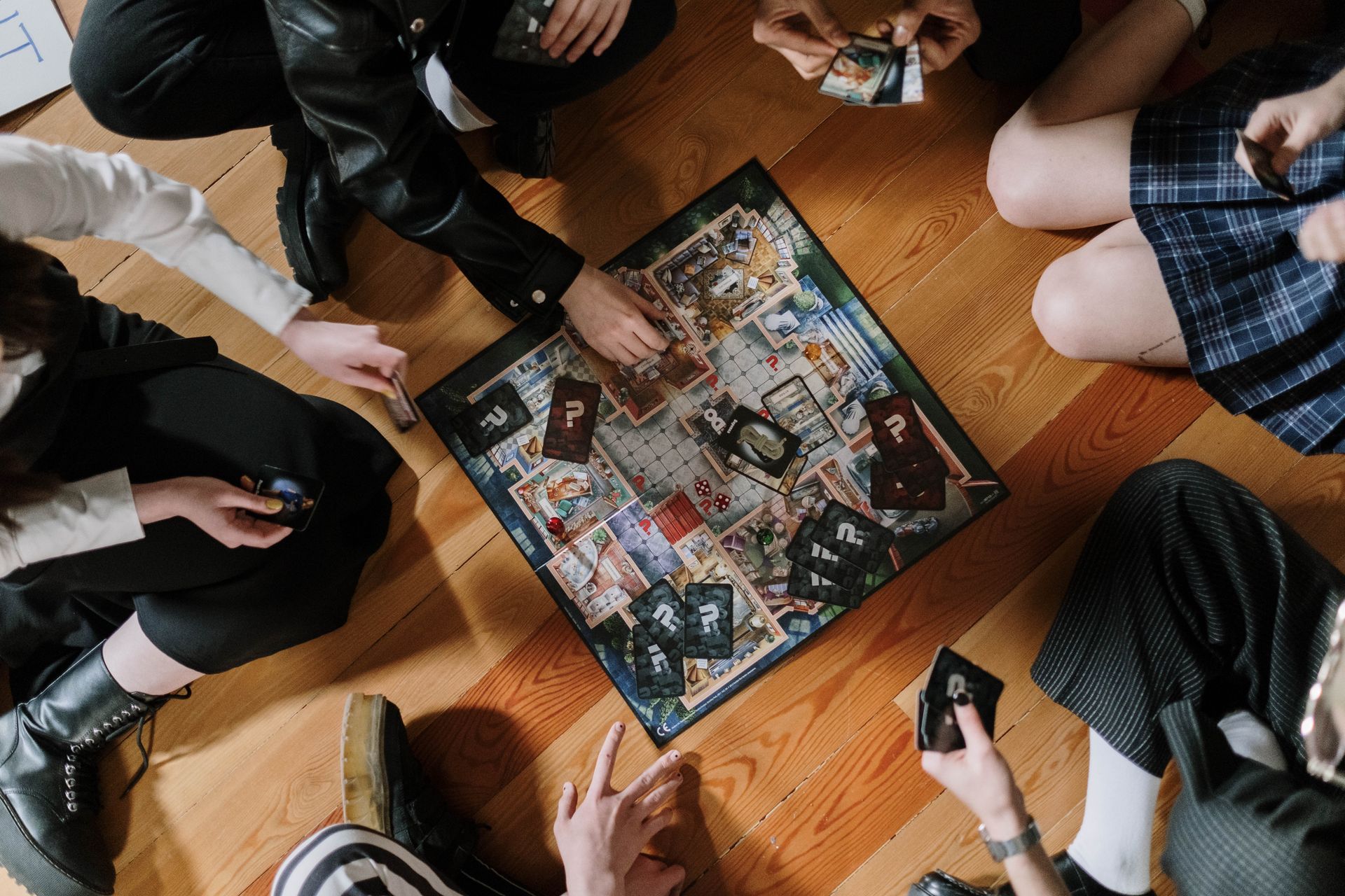 Overhead view of friends playing a board game on a wooden floor