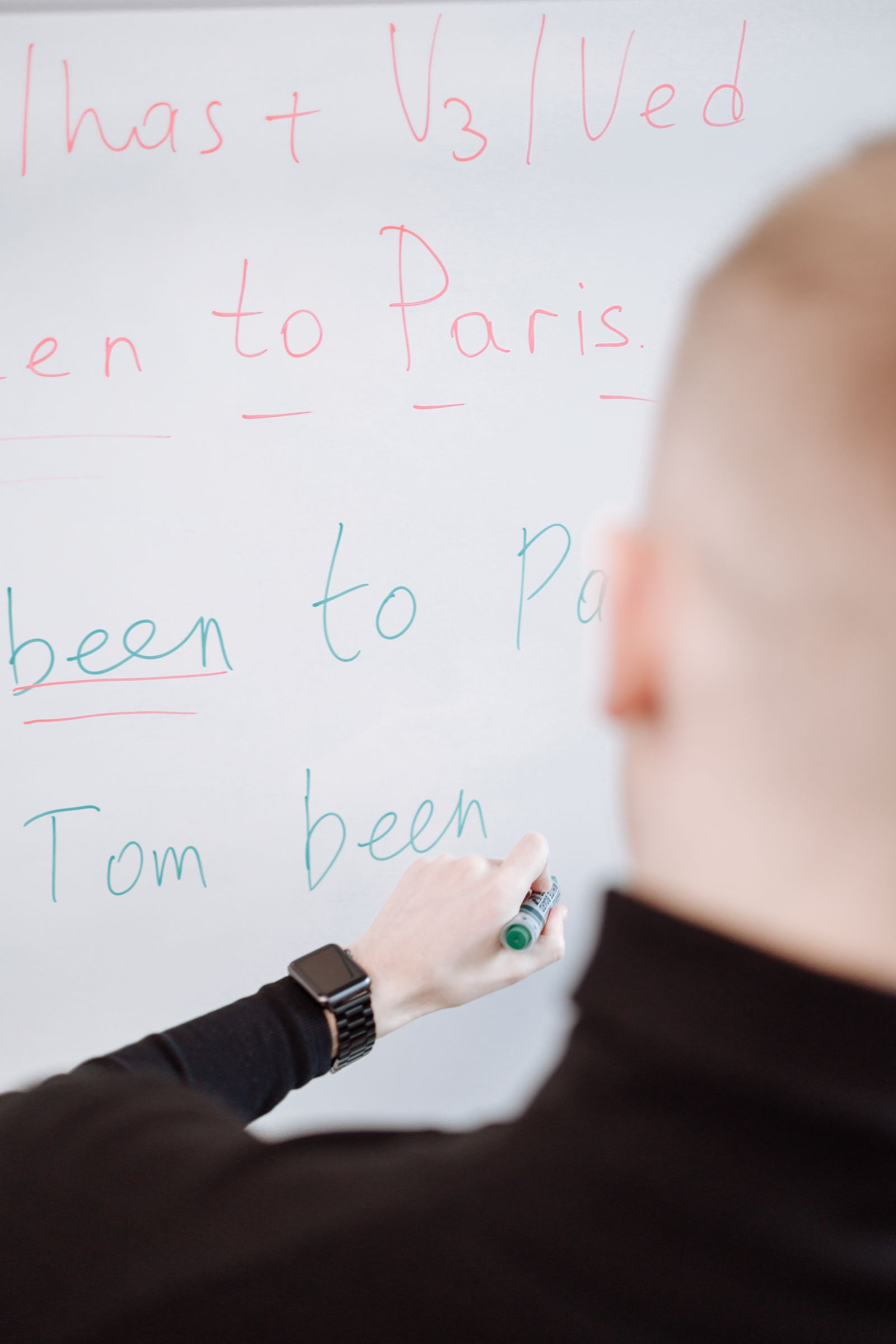 Person writing grammar instructions on a whiteboard