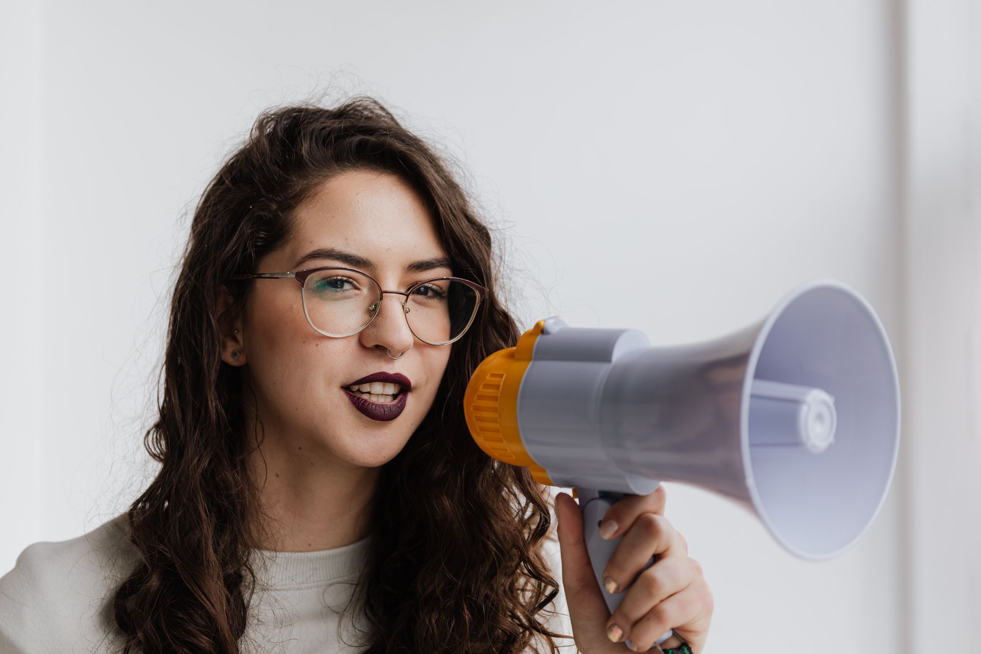 Confident woman speaking into a megaphone in a bright room