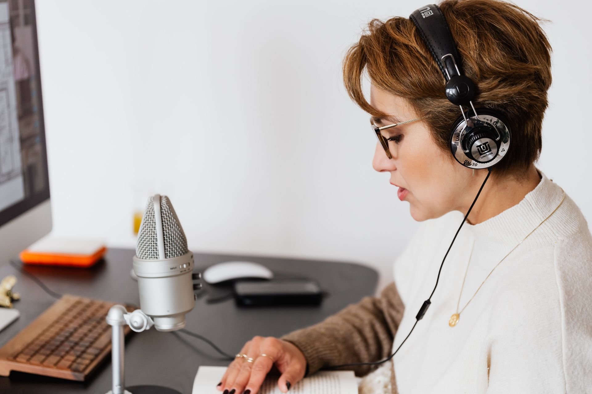 Woman with headphones speaking into a microphone in a home studio