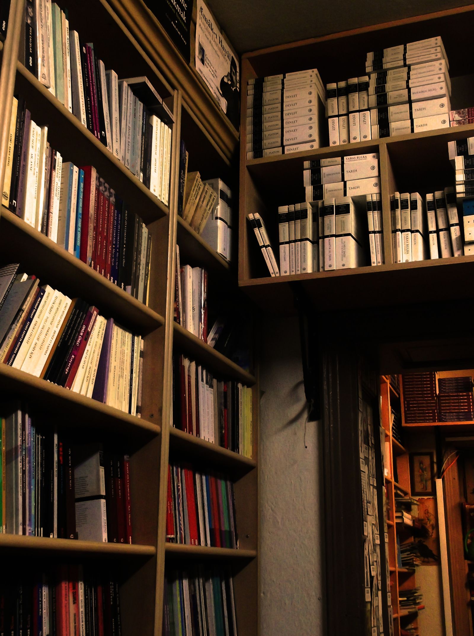 Wooden bookshelves filled with various books in a dimly lit library corner