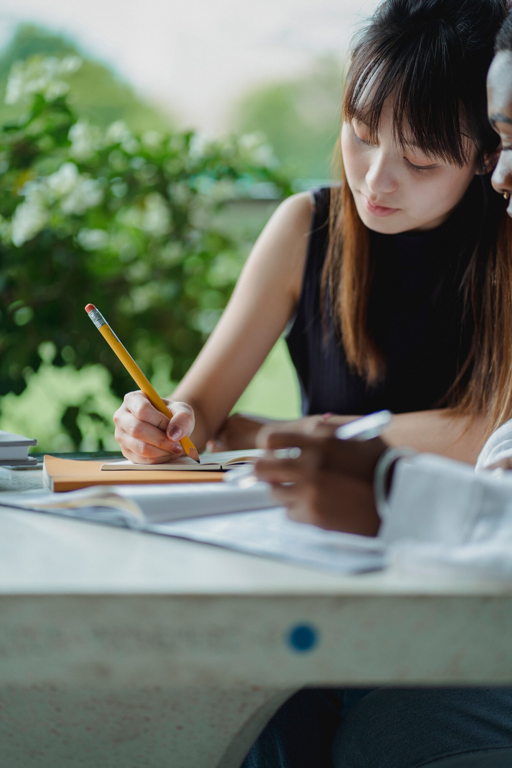 Two students concentrate on their studies outdoors, showcasing teamwork and focus.