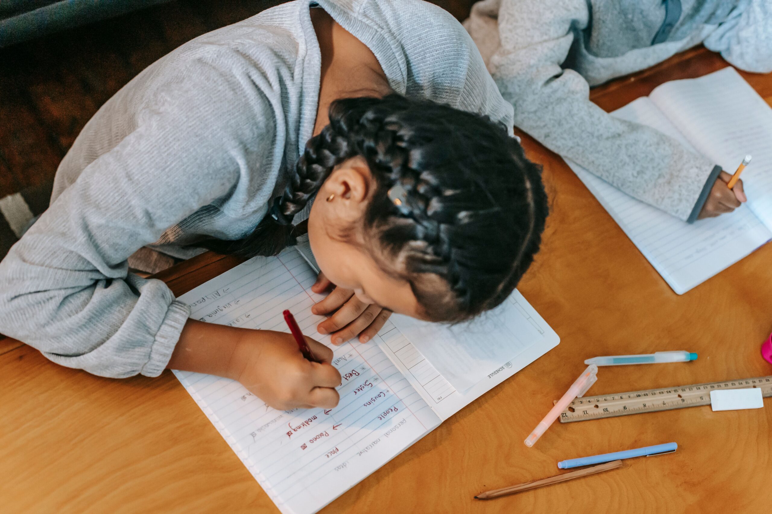 Two children focused on doing homework, collaborating at a wooden table indoors.