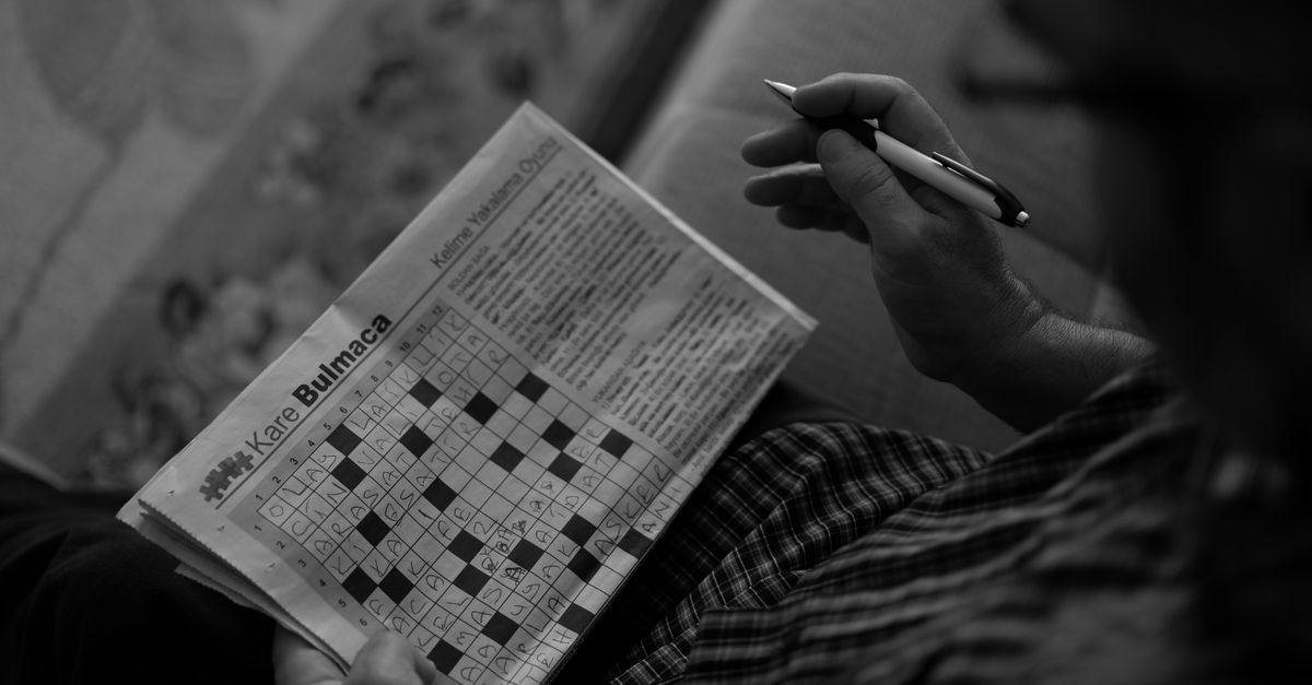 Person concentrating on solving a crossword puzzle