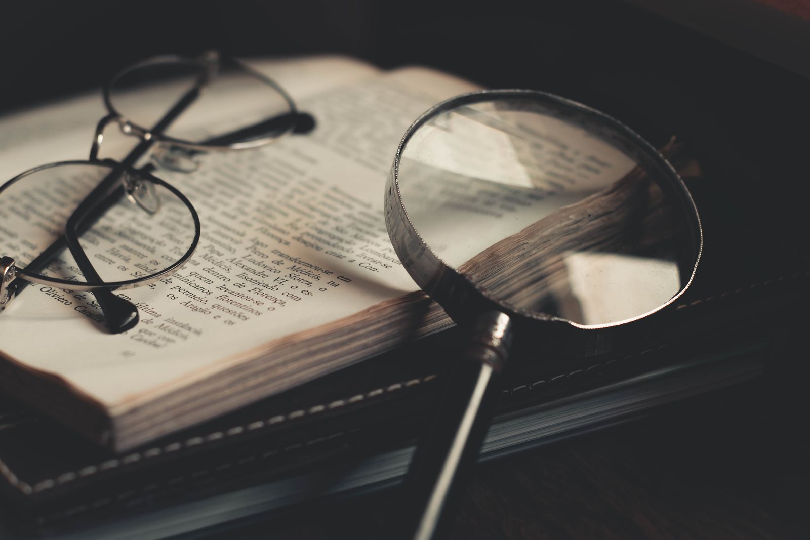 Magnifying glass and eyeglasses on an open book