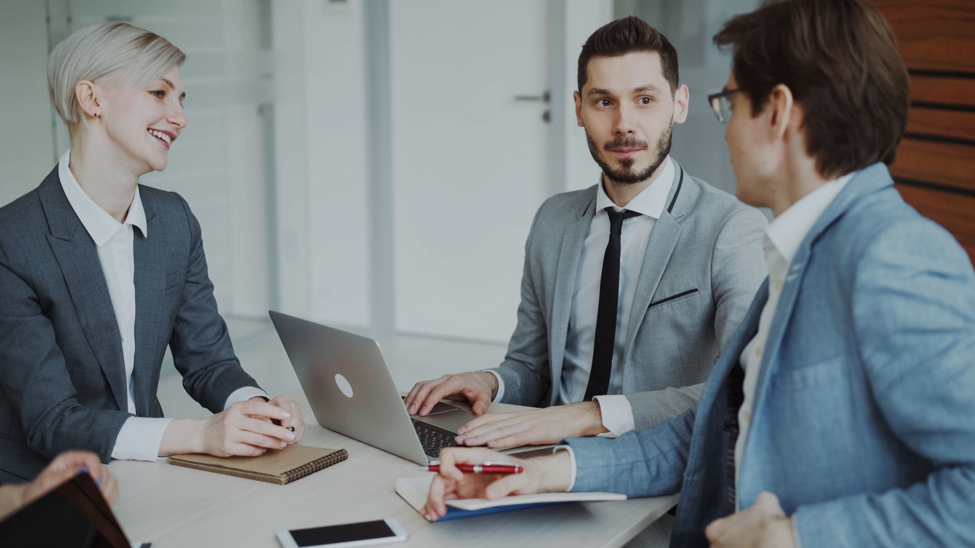 Business professionals in a meeting with laptops and notebooks, discussing strategy