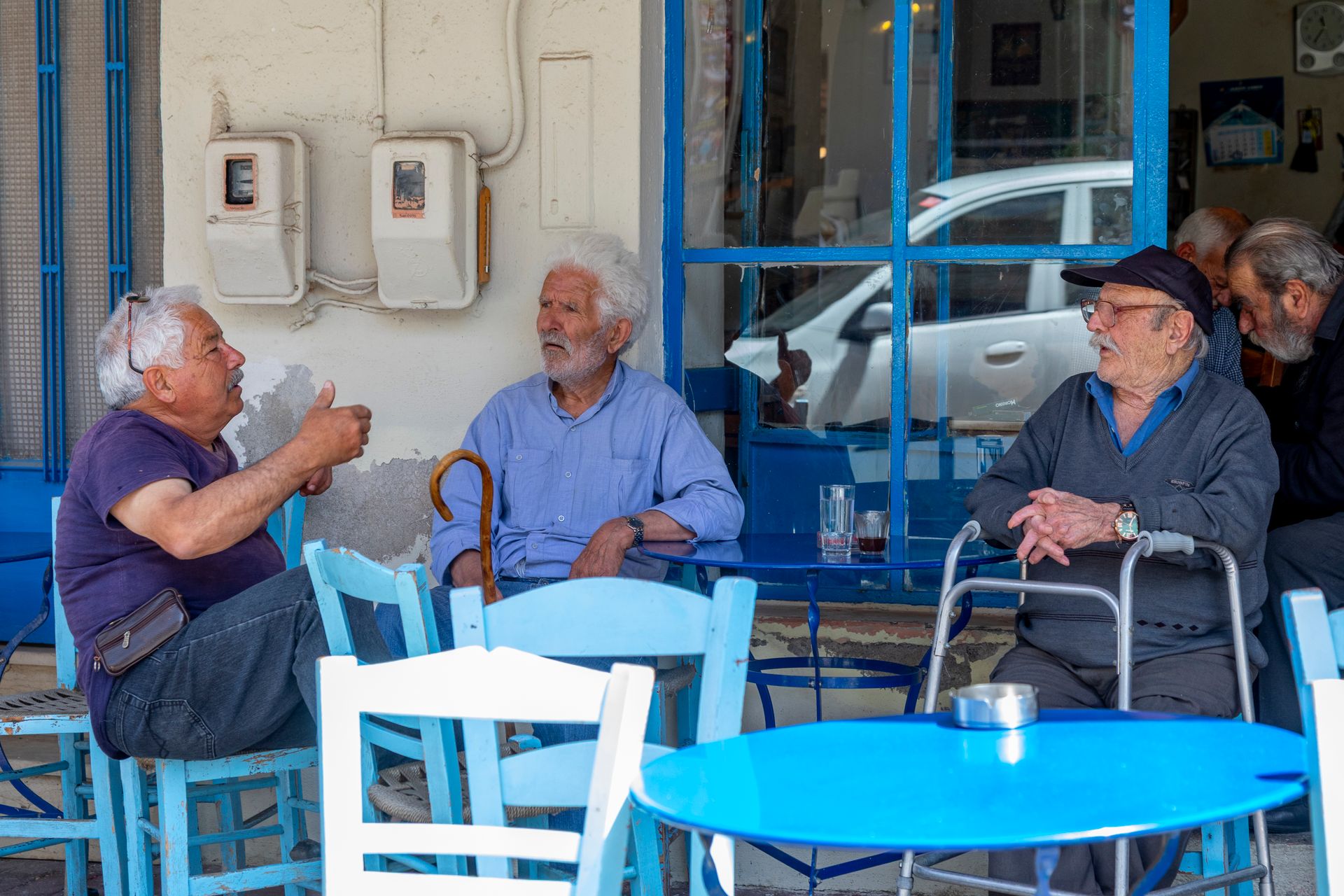 Three elderly men engaged in lively conversation at a traditional cafe terrace