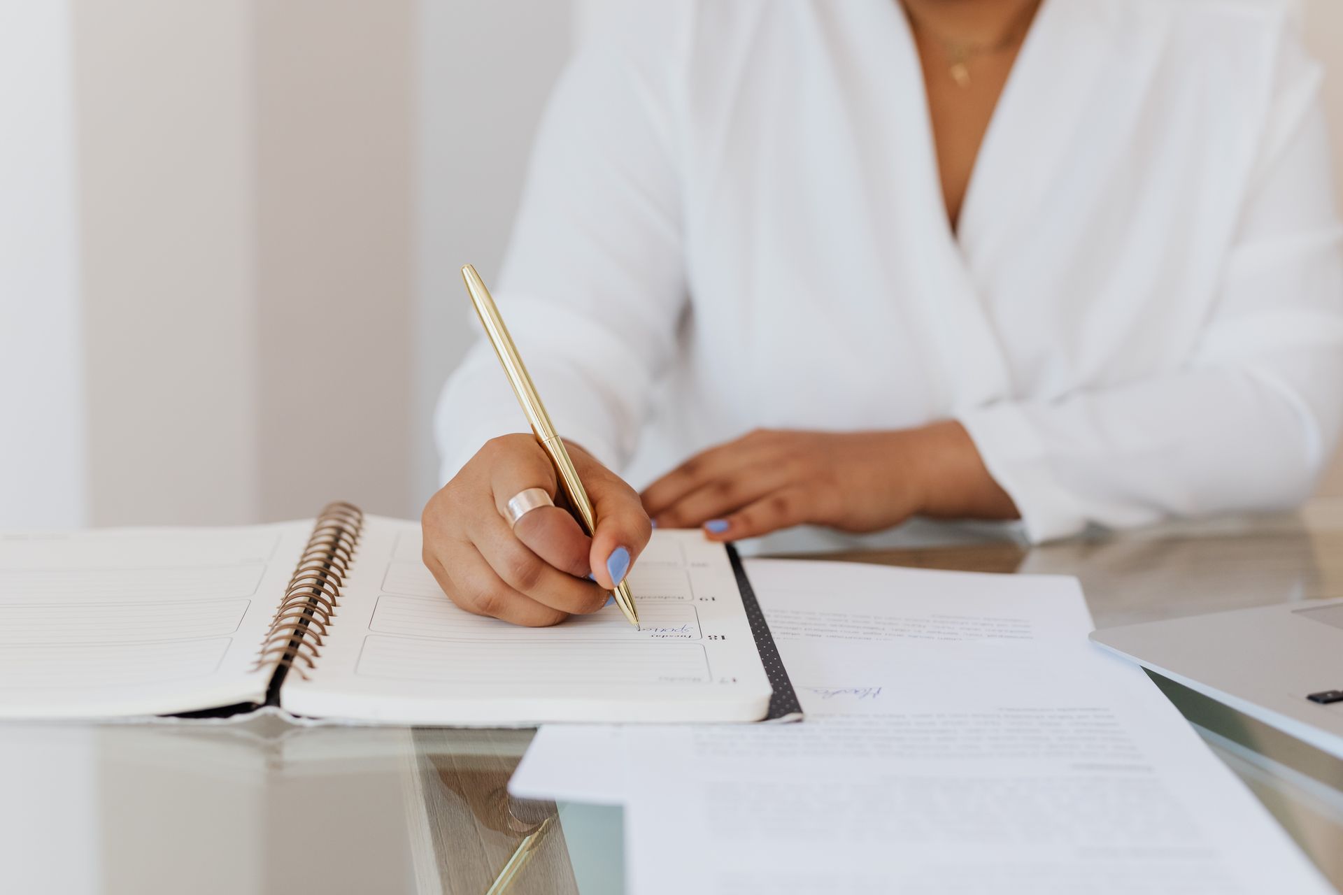 Person writing strategy notes in a planner with a gold pen