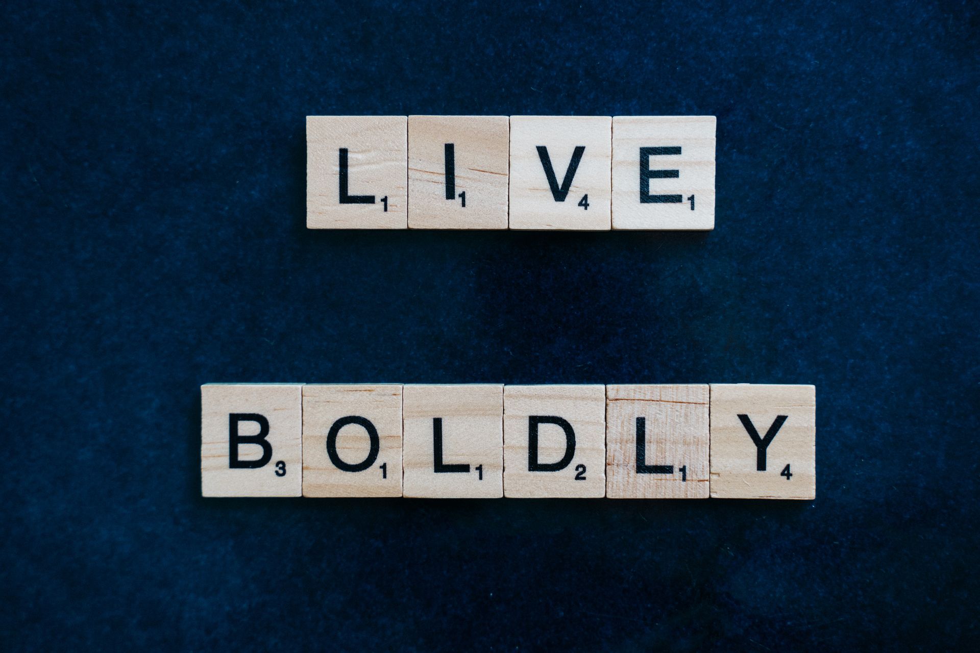 Scrabble tiles spelling Live Boldly on a blue surface