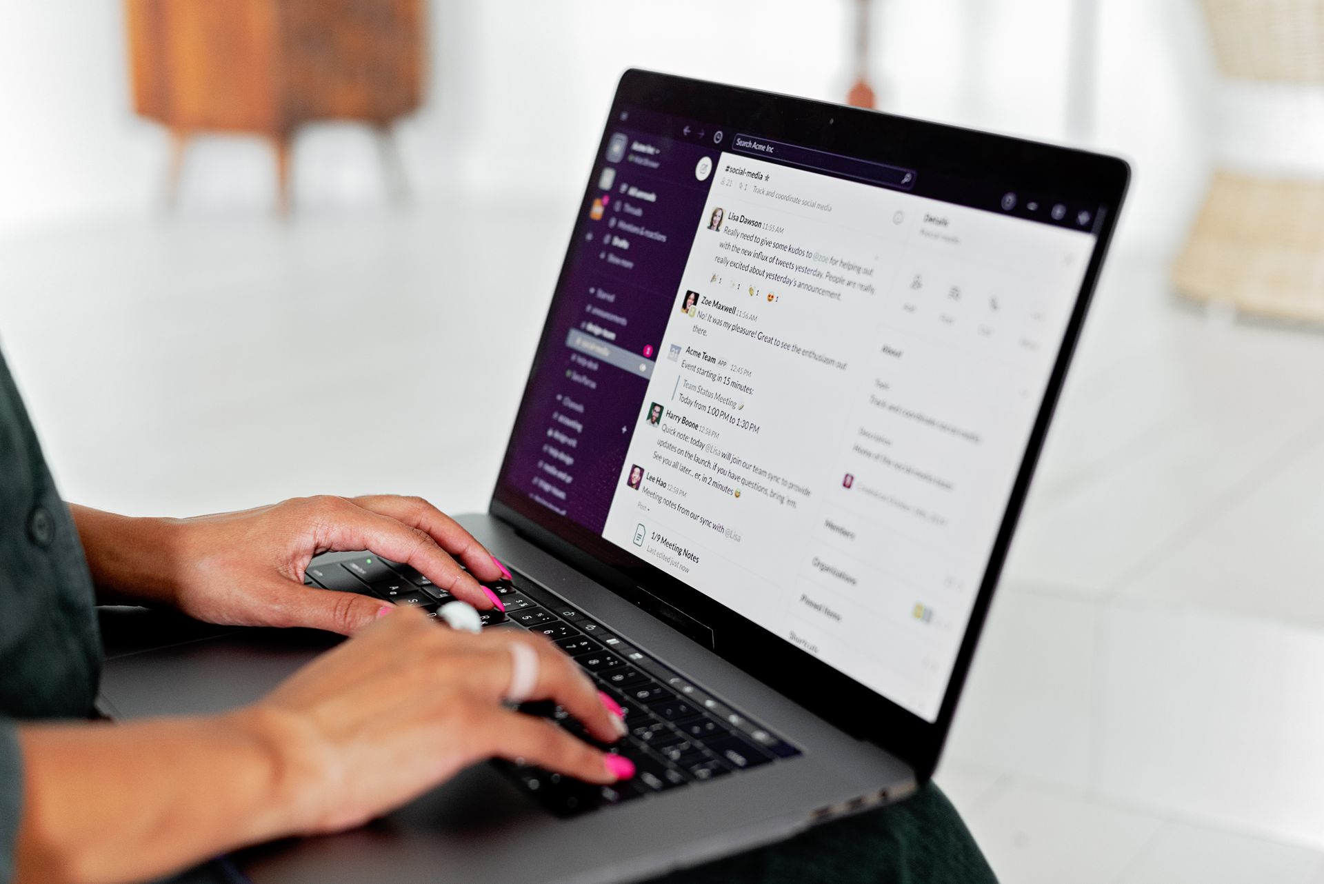 A woman types on a laptop using a messaging app in a modern office setting