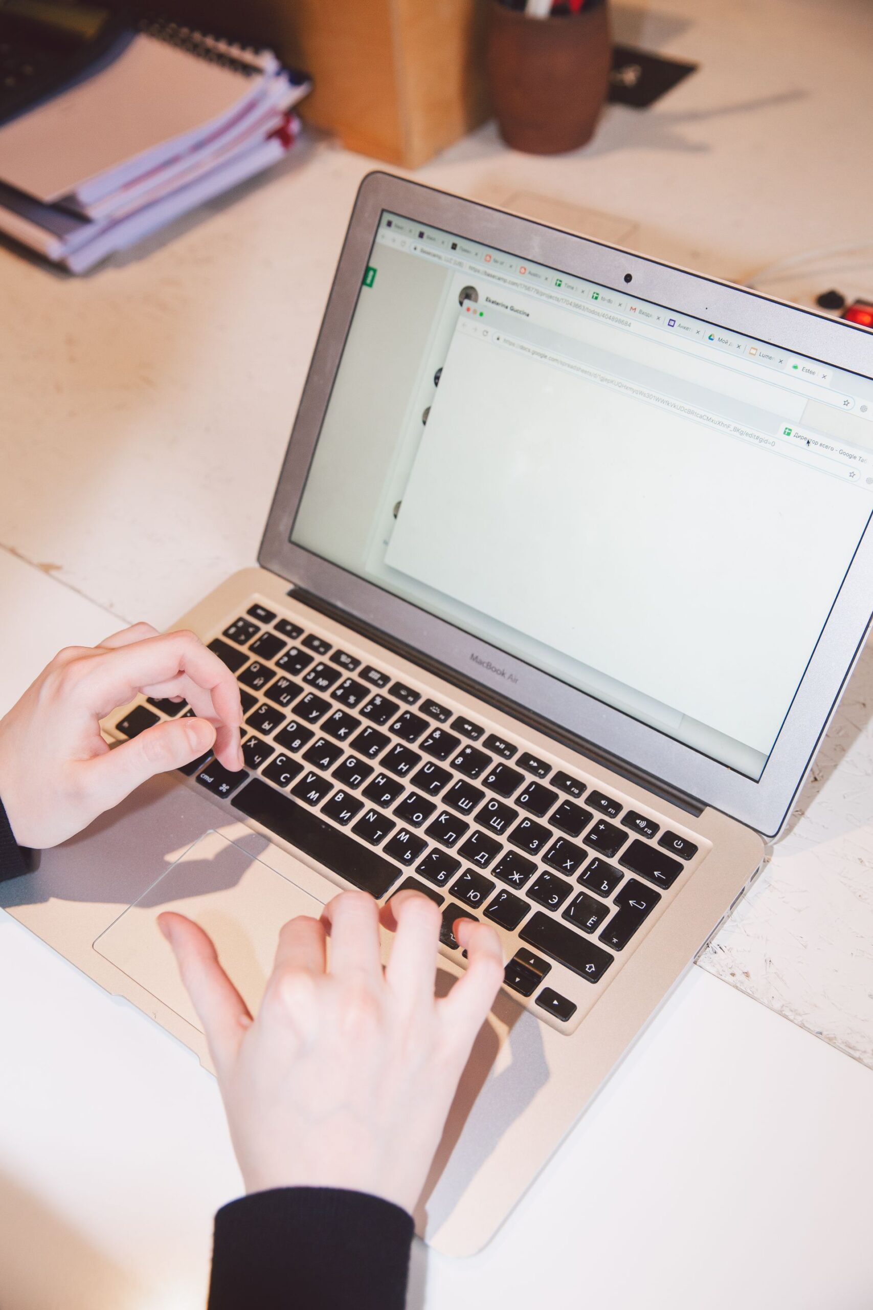 Close-up of hands typing on a laptop at an office desk, suggesting work or online communication