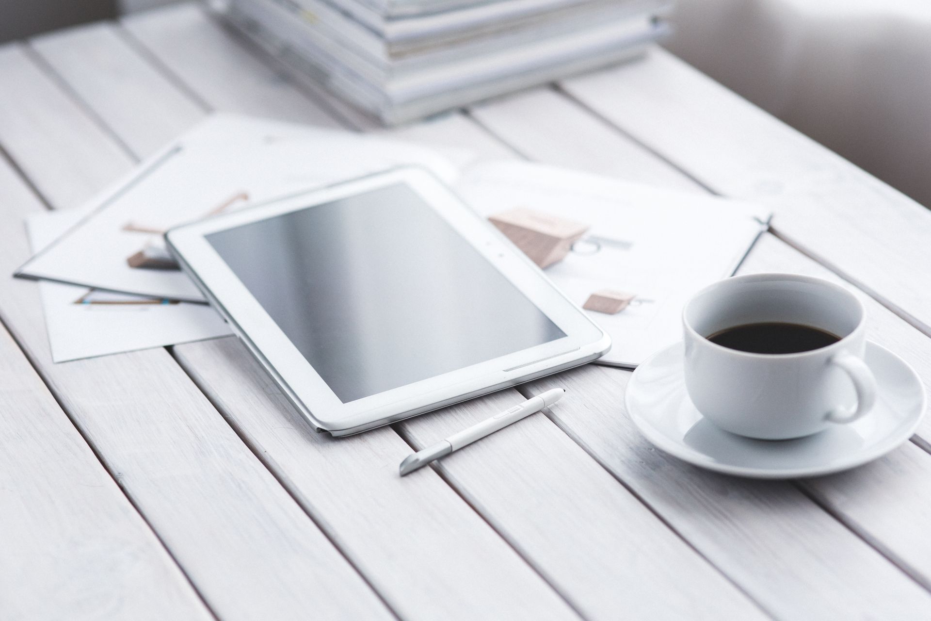 White tablet with stylus and coffee cup on modern office desk setup