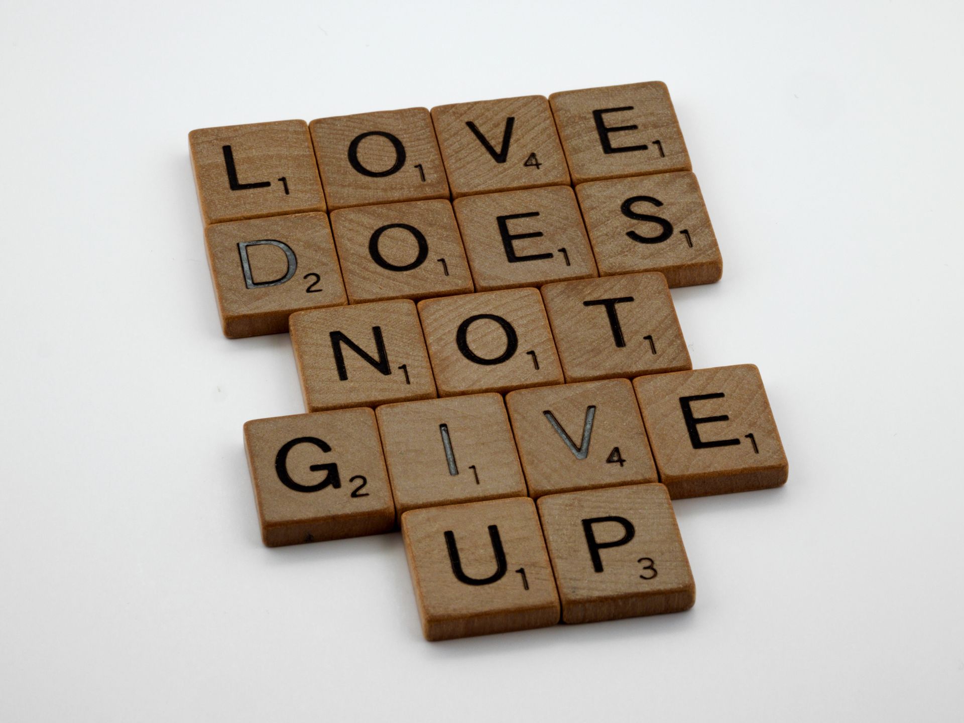 Scrabble tiles spelling Love Always Protects on white