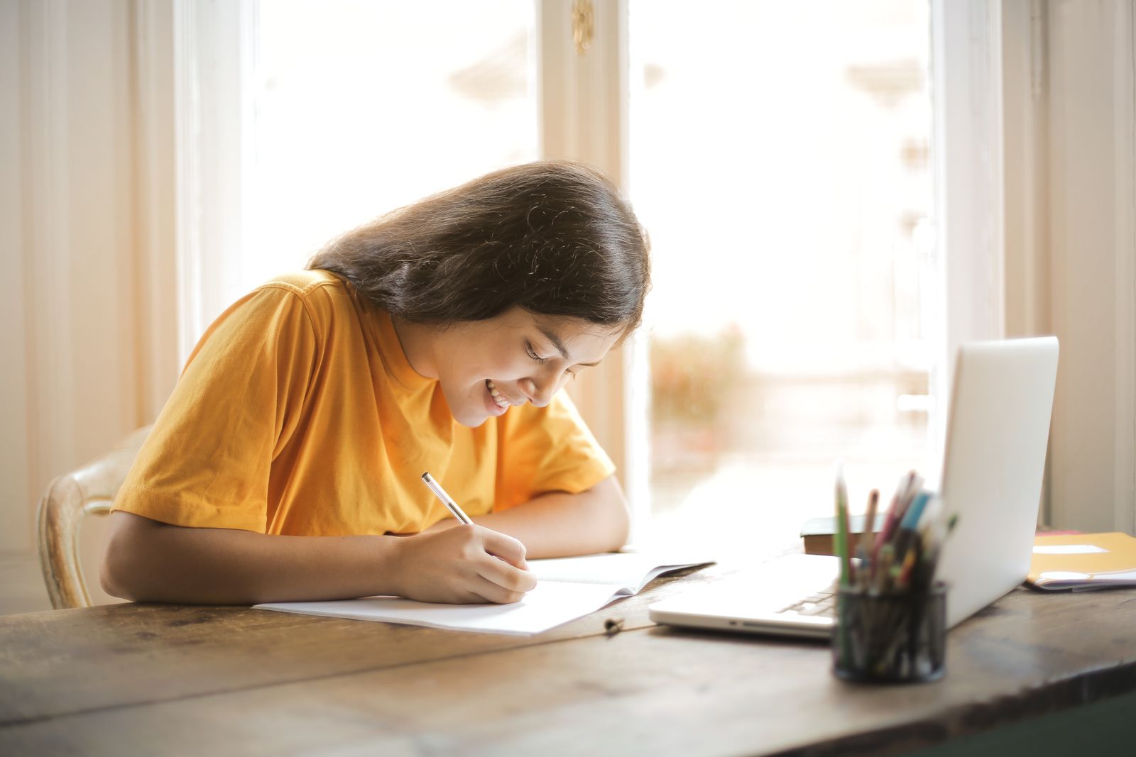 Woman in a yellow shirt writing on paper