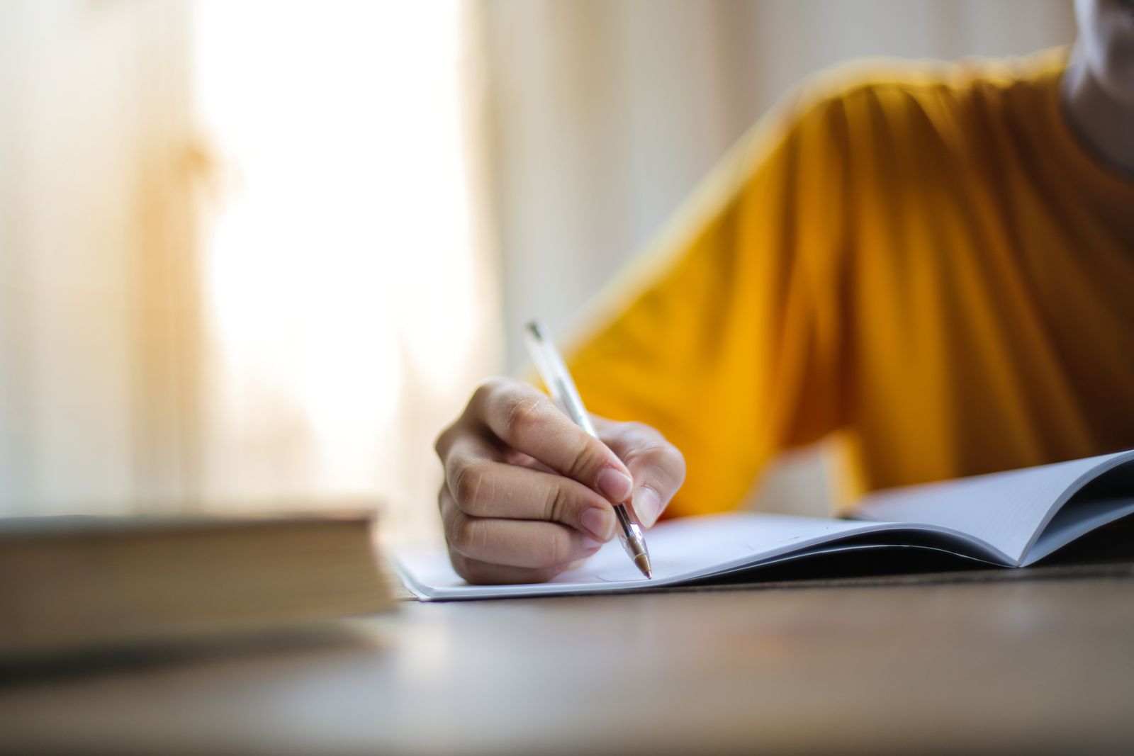 Person writing with a pen in soft focus