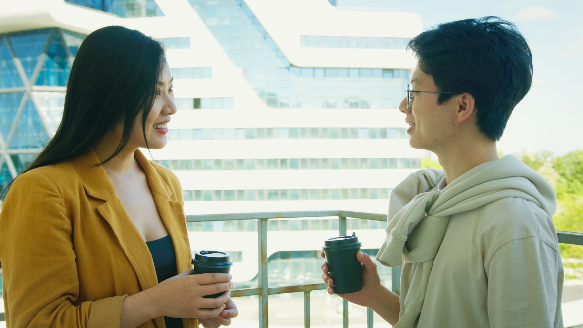 Two friends chatting over coffee on an urban balcony