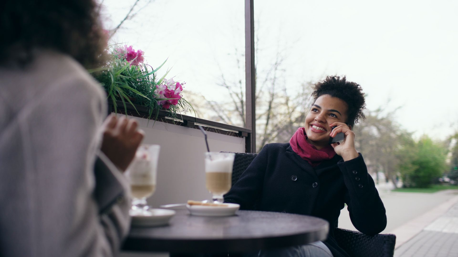 Woman chatting on the phone while enjoying coffee outdoors