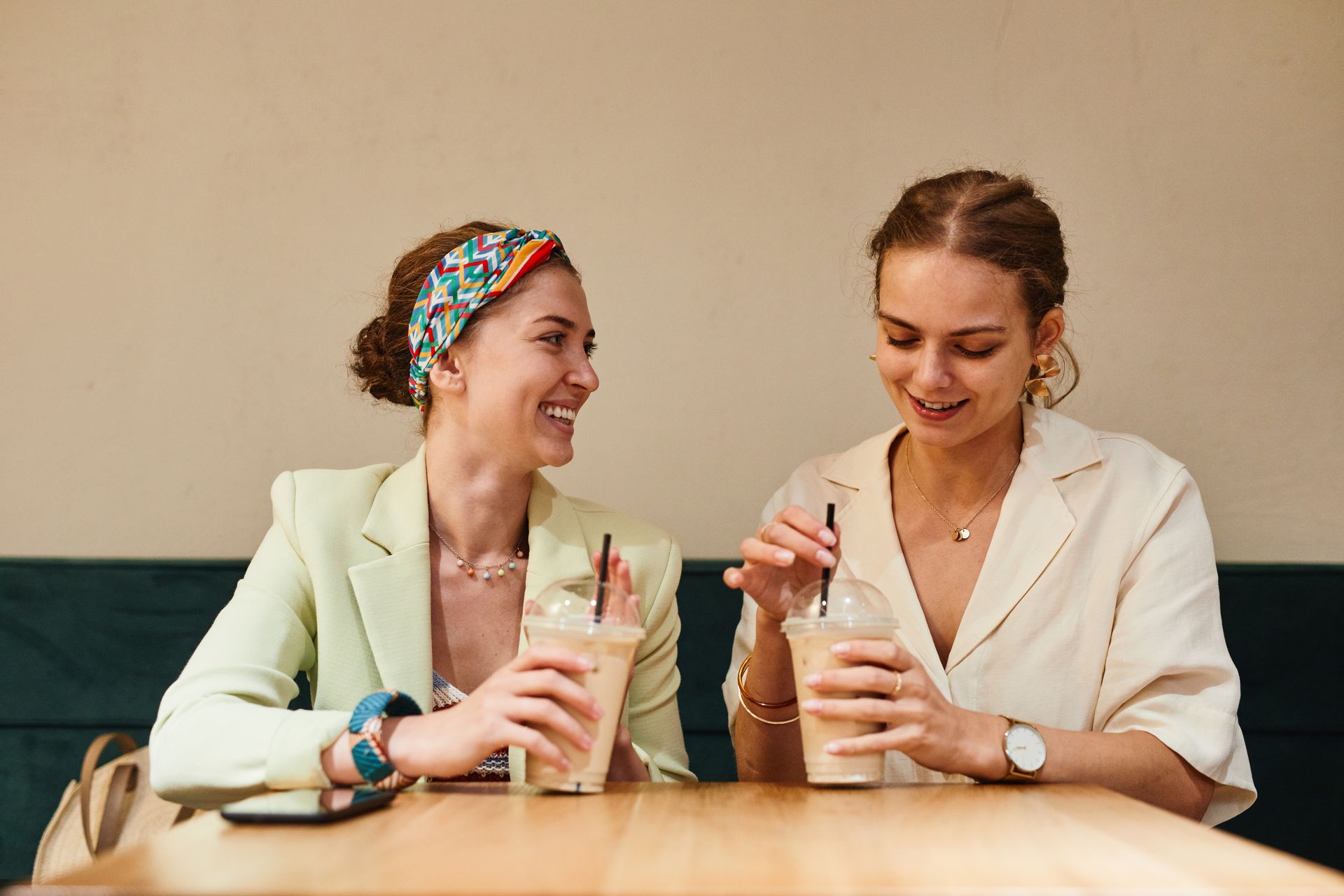 Two young women having a lively conversation over iced coffee