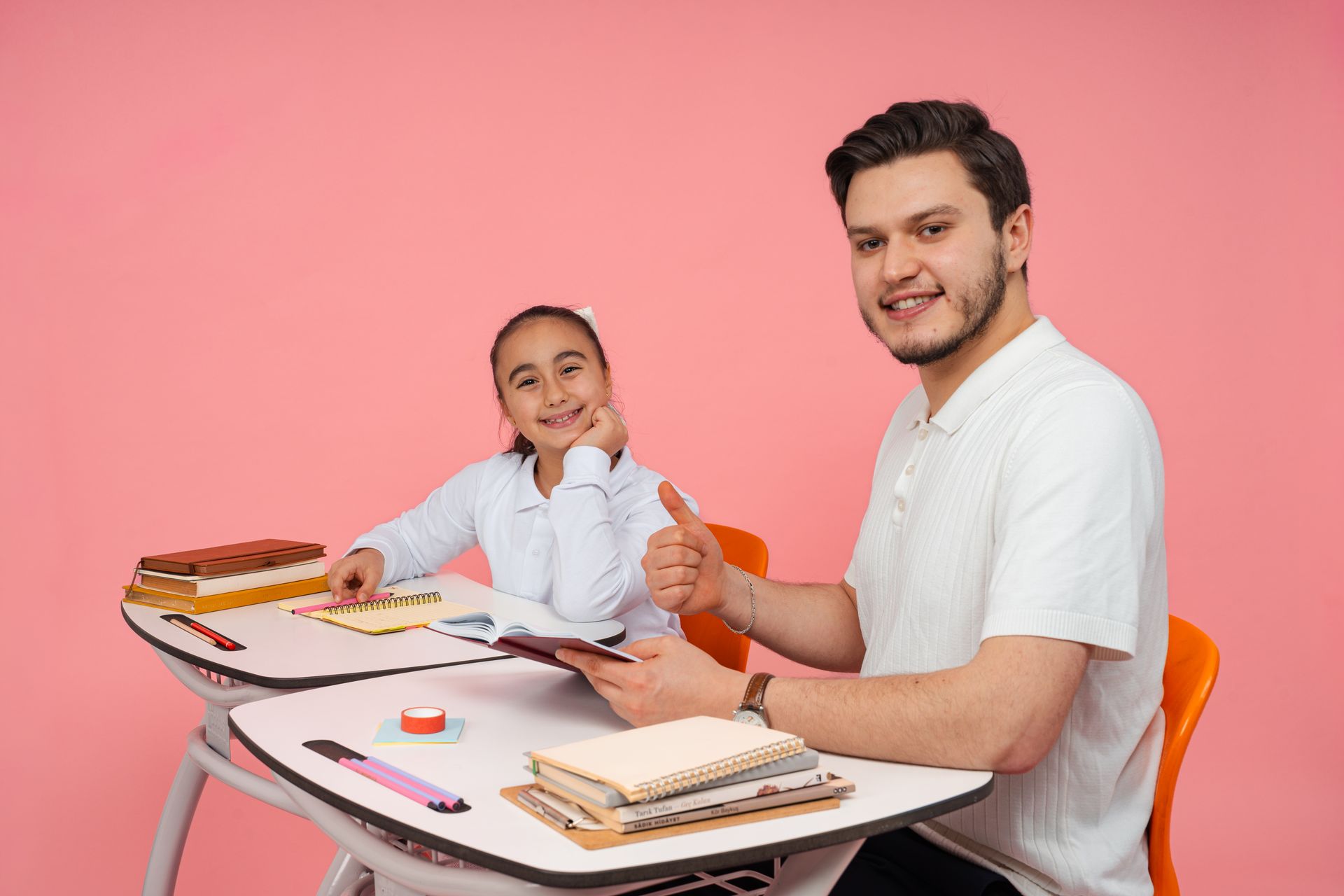 Teacher and student smiling together at a classroom desk