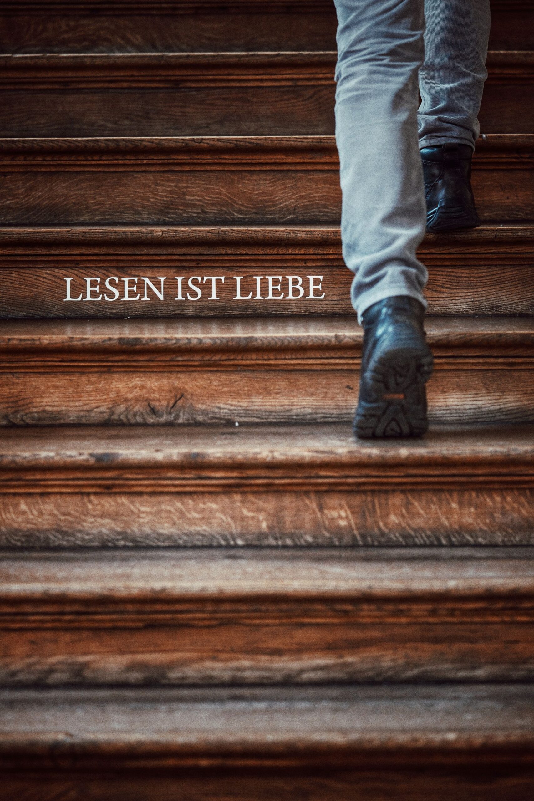 Person walking up a wooden staircase with the words LESEN IST LIEBE