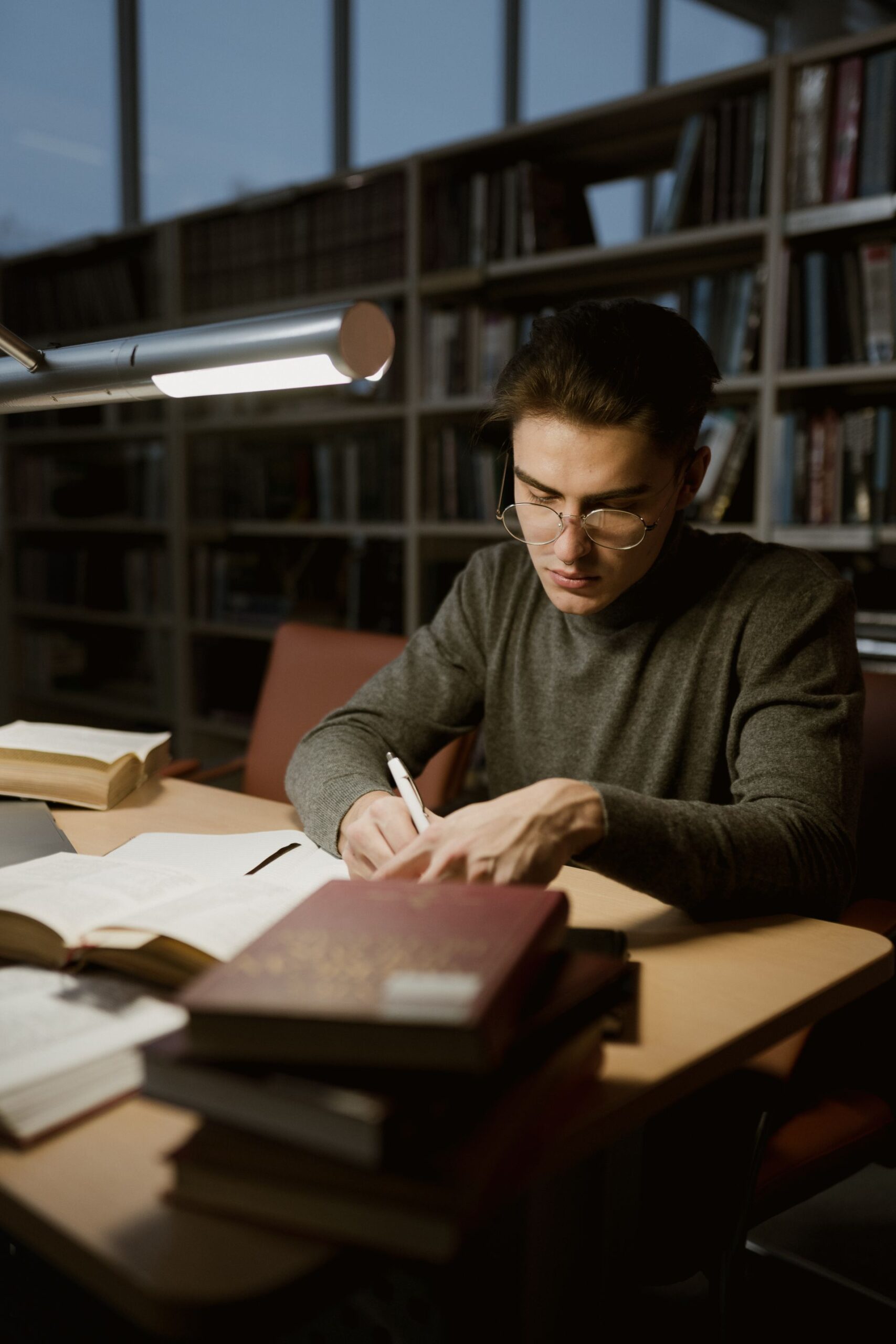 Young man studying with books in a library