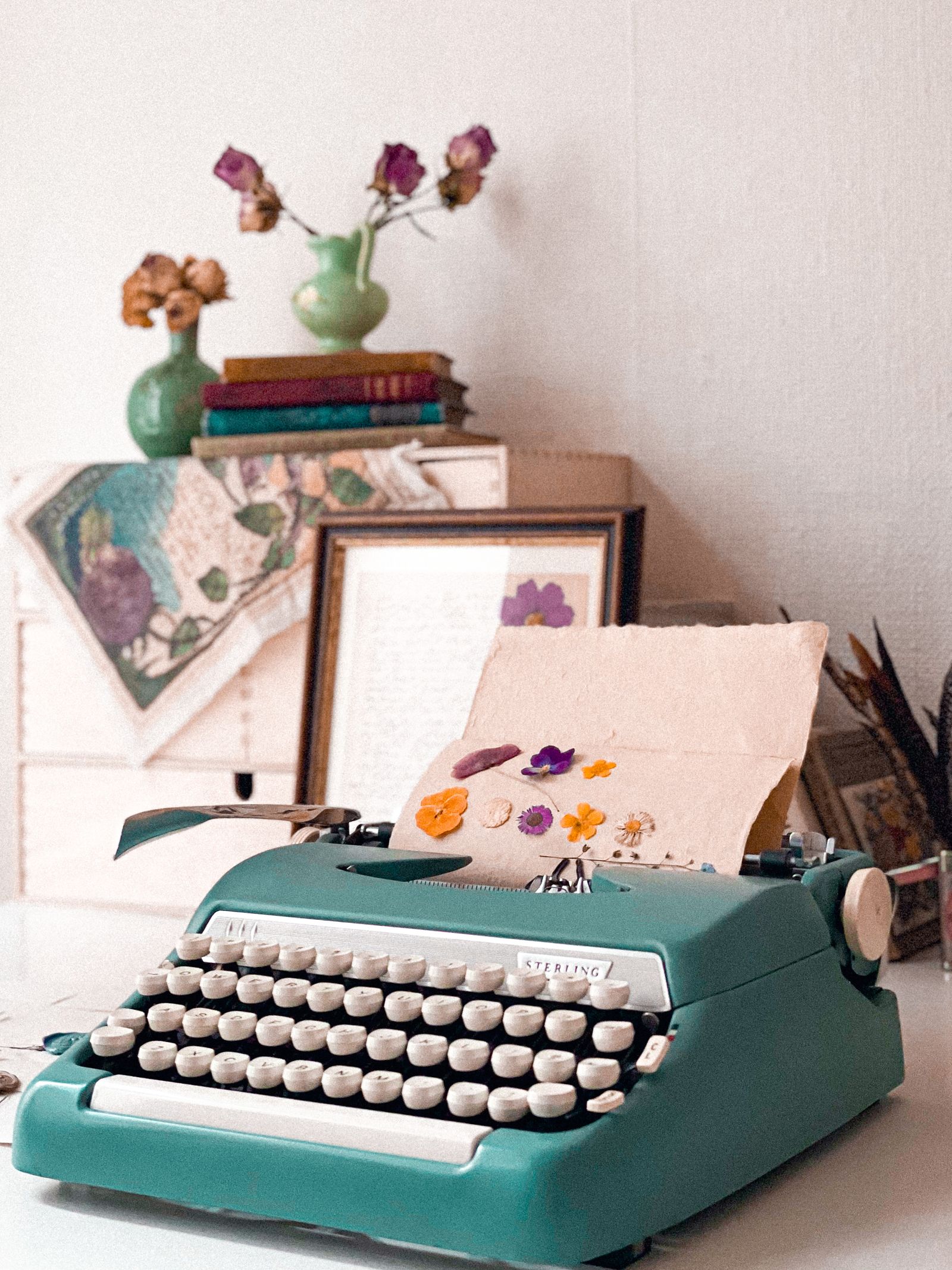 Vintage typewriter with flowers, books, and decor on a desk setting