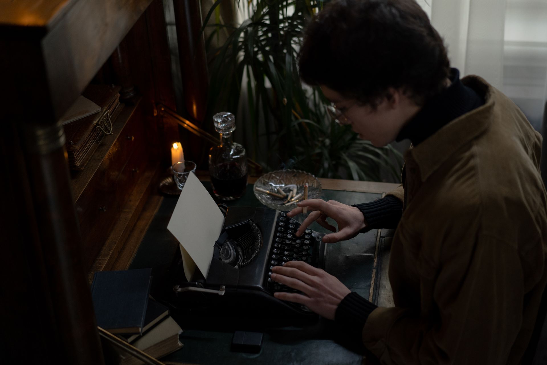 Man typing on a vintage typewriter by candlelight