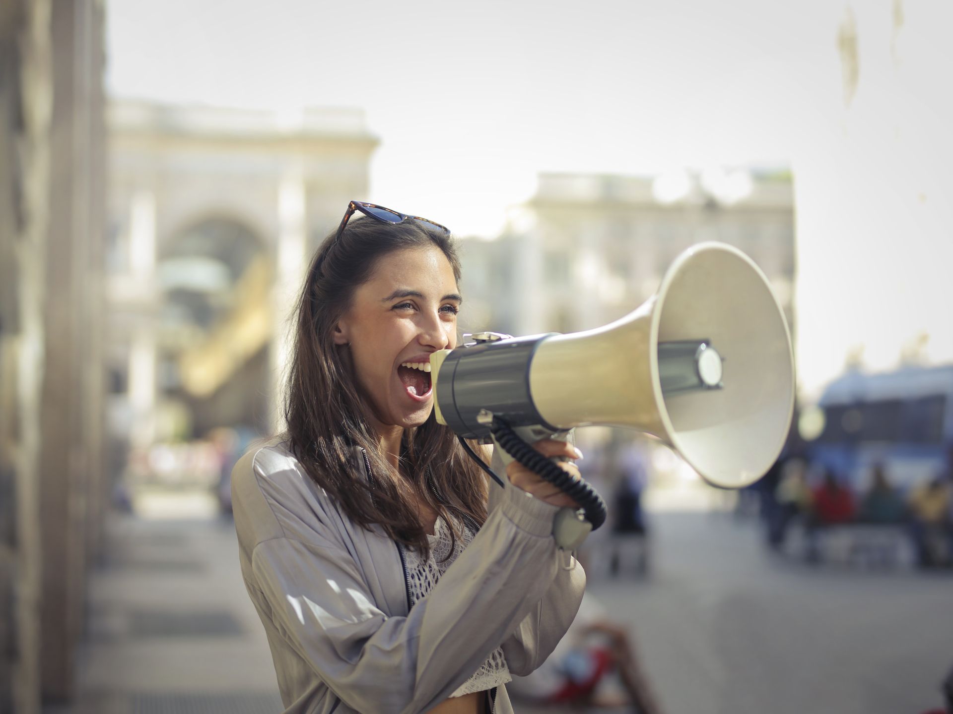 Cheerful woman shouting into a megaphone outdoors